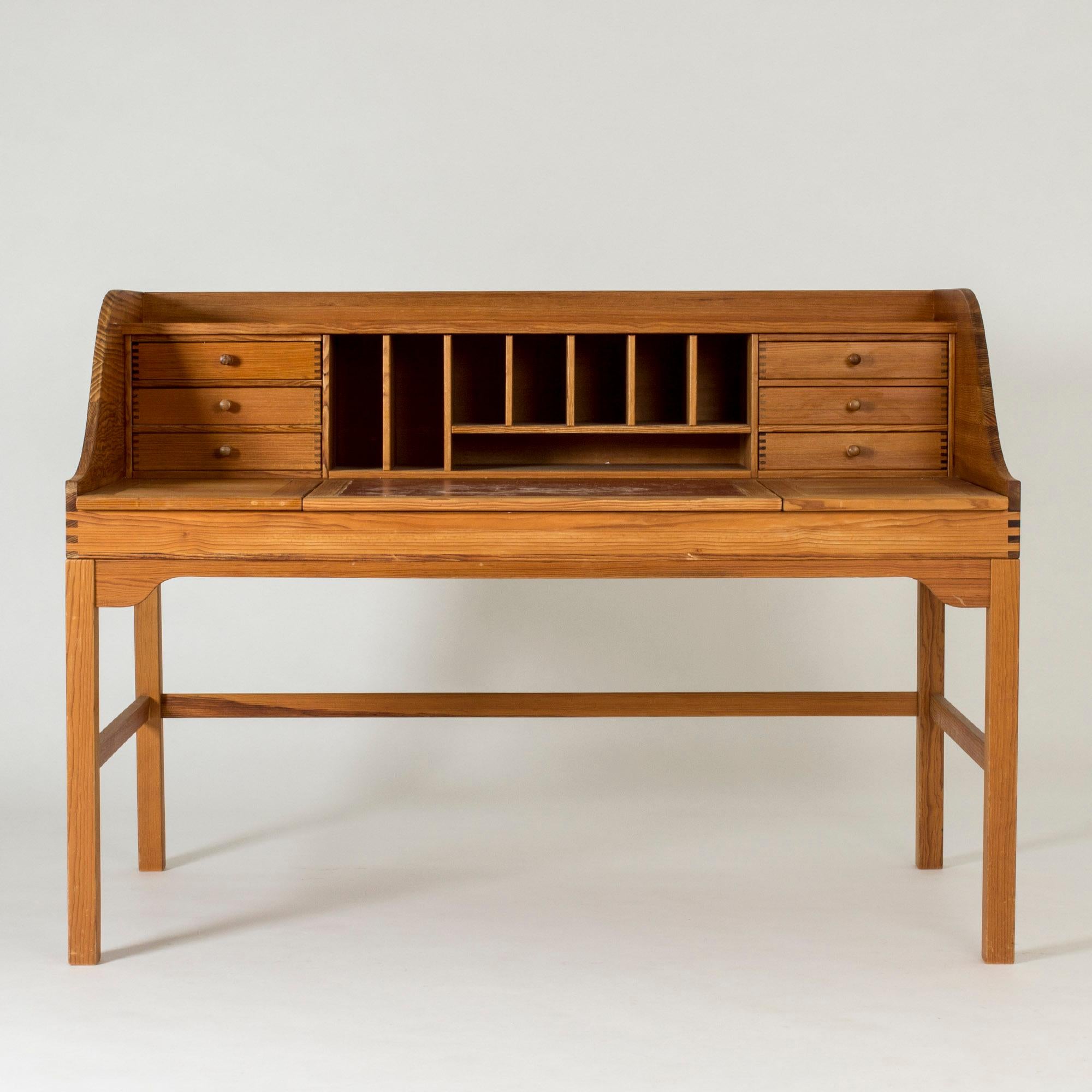 Elegant desk by Andreas Hansen, made in rustic Oregon pine with distinct woodgrain and joinery. The tabletop is dressed with leather in the middle, and opens up to reveal storage underneath. Several drawers and shelves provide optimal