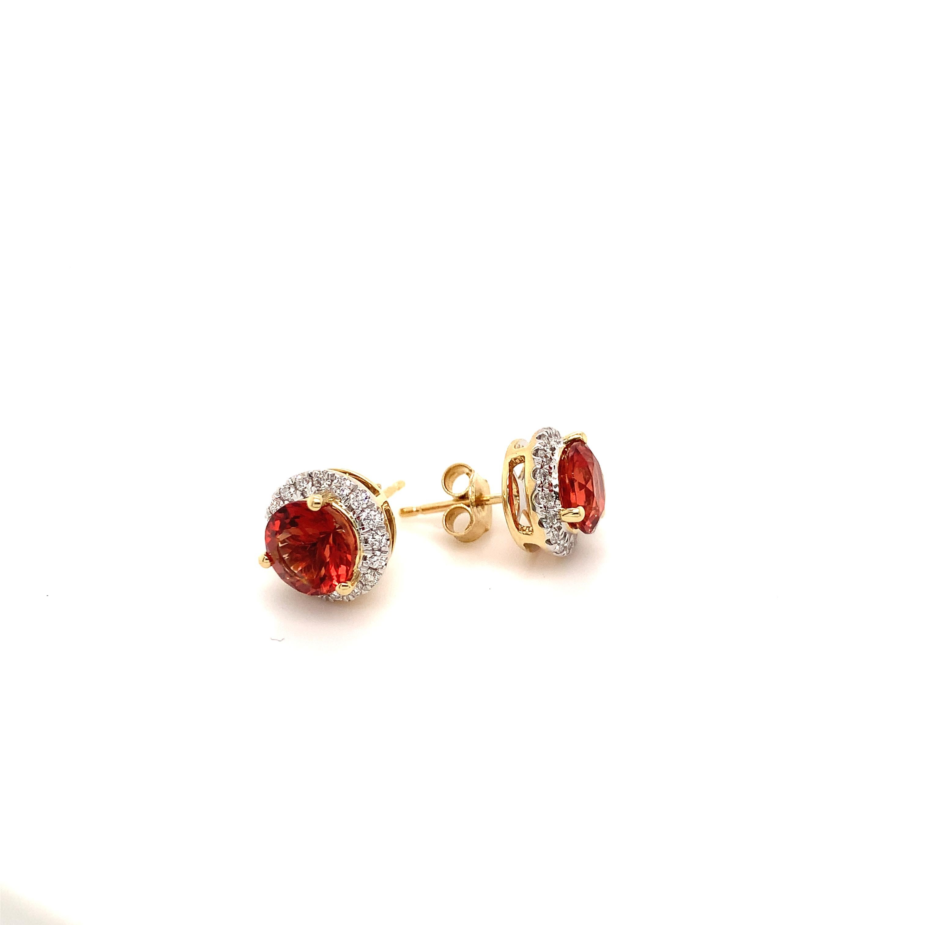 Orange / red Oregon Sunstone are hard to find, particularly a matched pair. This pair of 7 mm brilliant faceted rounds weigh a total of 2.5 carats. The halo, two tone 14-karat gold stud earrings have a total of 44 Diamond, 22 in each earring, that