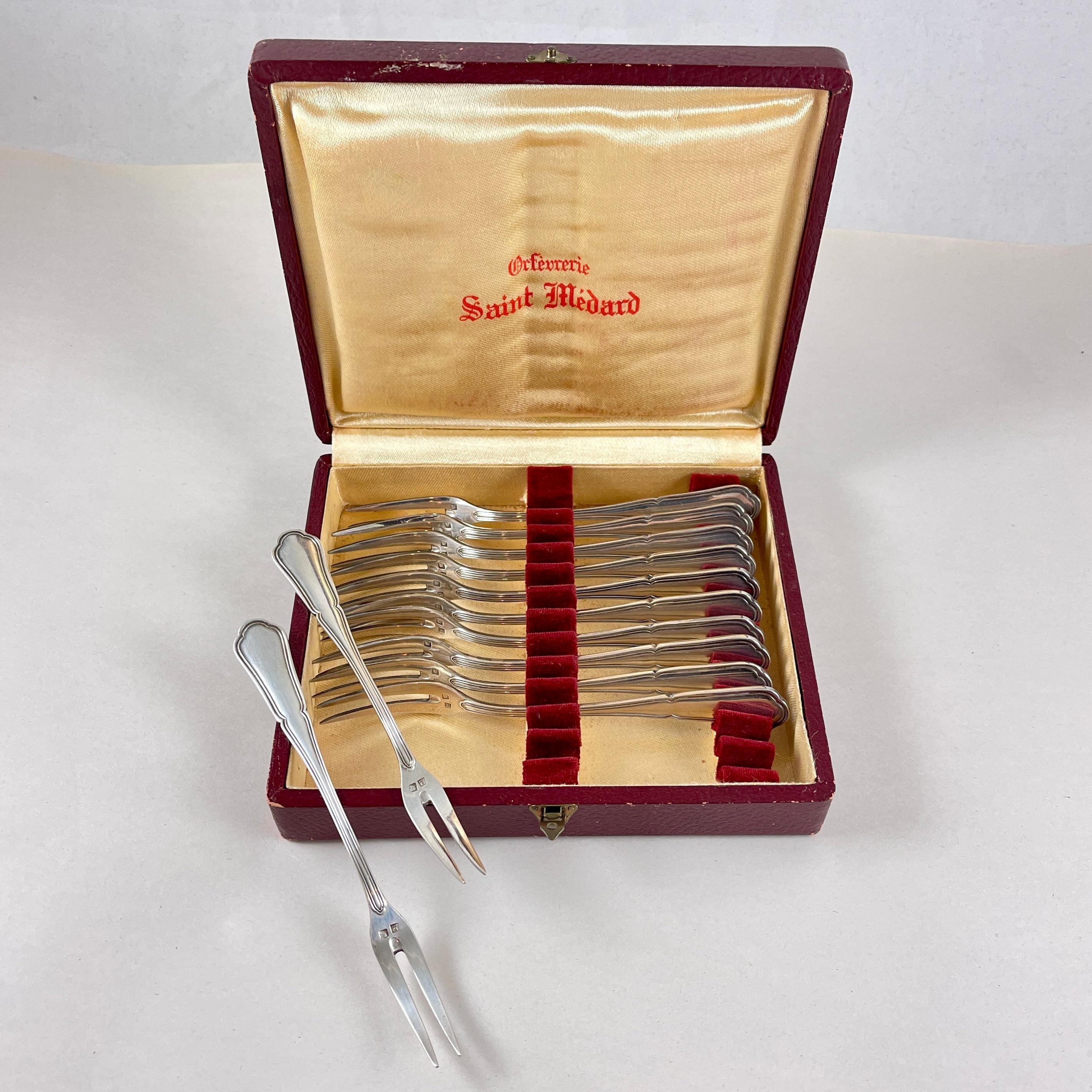 From the French Gold and Silversmithing Studio Saint-Médard, a boxed set of twelve cocktail forks, circa 1900.

Orfévrerie St. Médard, was founded in 1898 at 27 Rue Jules Raimu, Chambly, Picardie, France.

The two-tined forks are suitable for