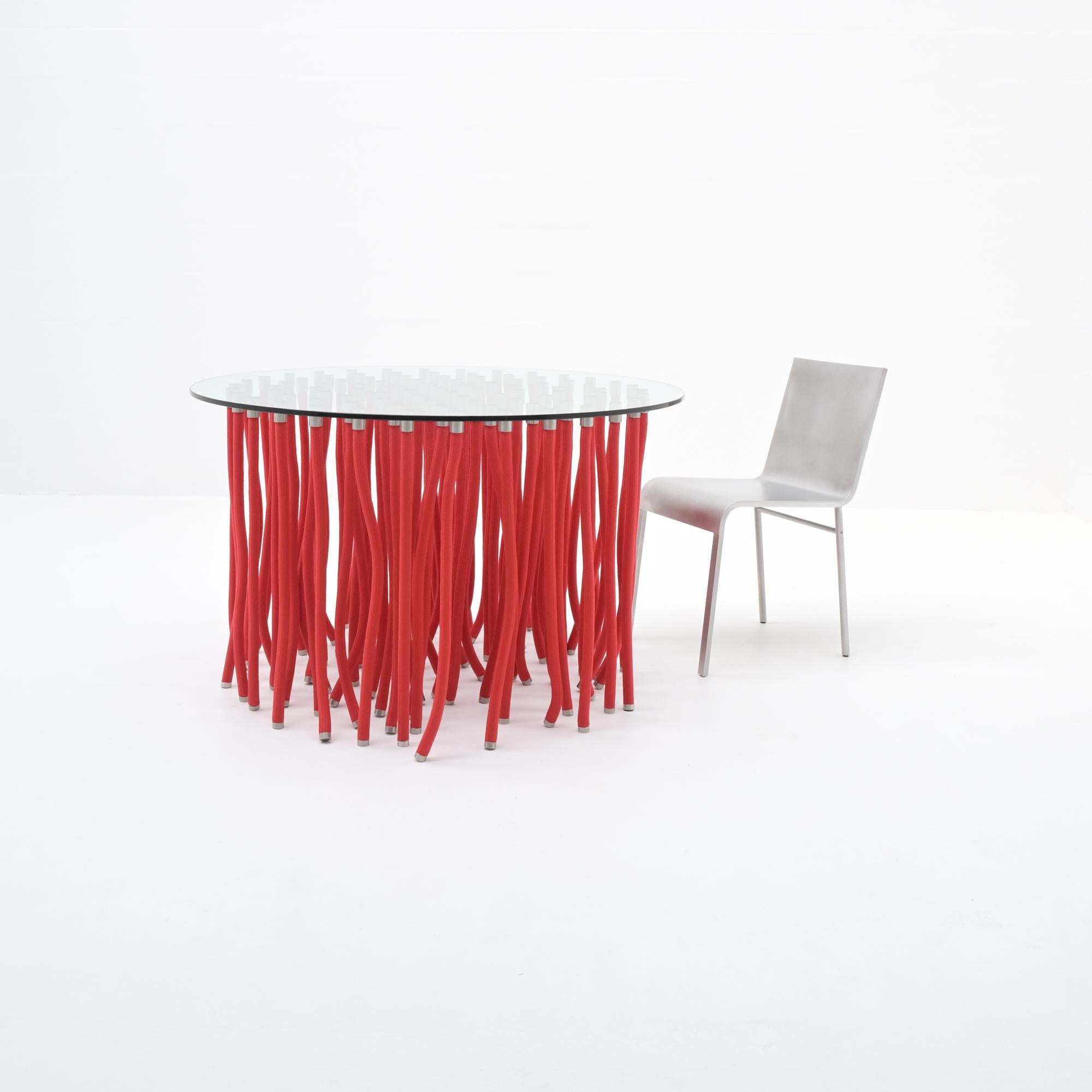 Dieser rote ORG-Esstisch wurde 2001 von Fabio Novembre für Cappellini entworfen. Dieser erstaunliche Tisch besteht aus einer Kristallglasplatte, die von einem mit Polypropylen ummantelten Stahlseil mit freiliegenden Edelstahlbeschlägen getragen