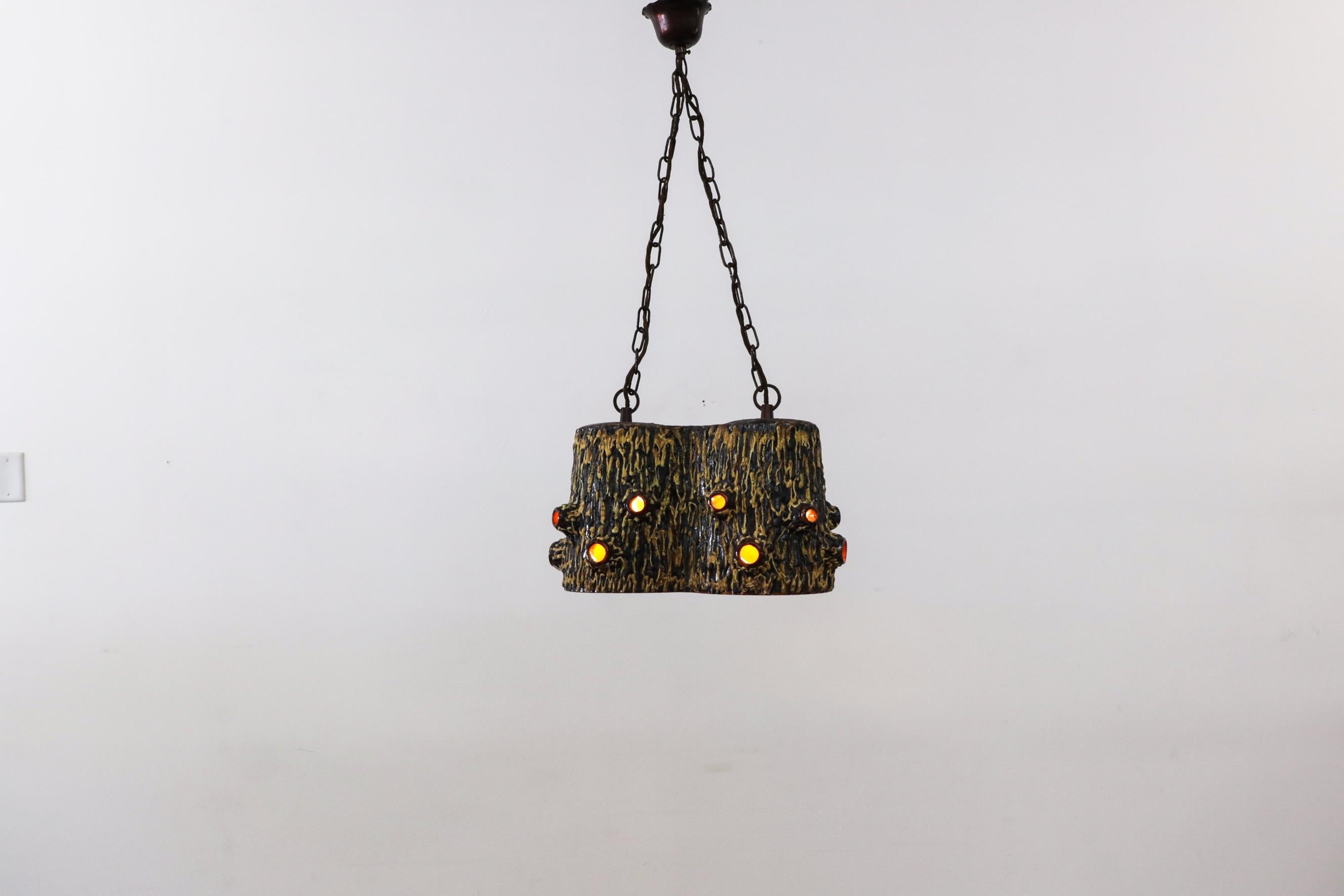 Beautiful, organic shaped ceramic chandelier with bark textured outside and bright orange glazed interior. This heavy ceramic pendant light is held by brutalist style double chain hardware and matching canopy. The amoeba-like fixture has a double