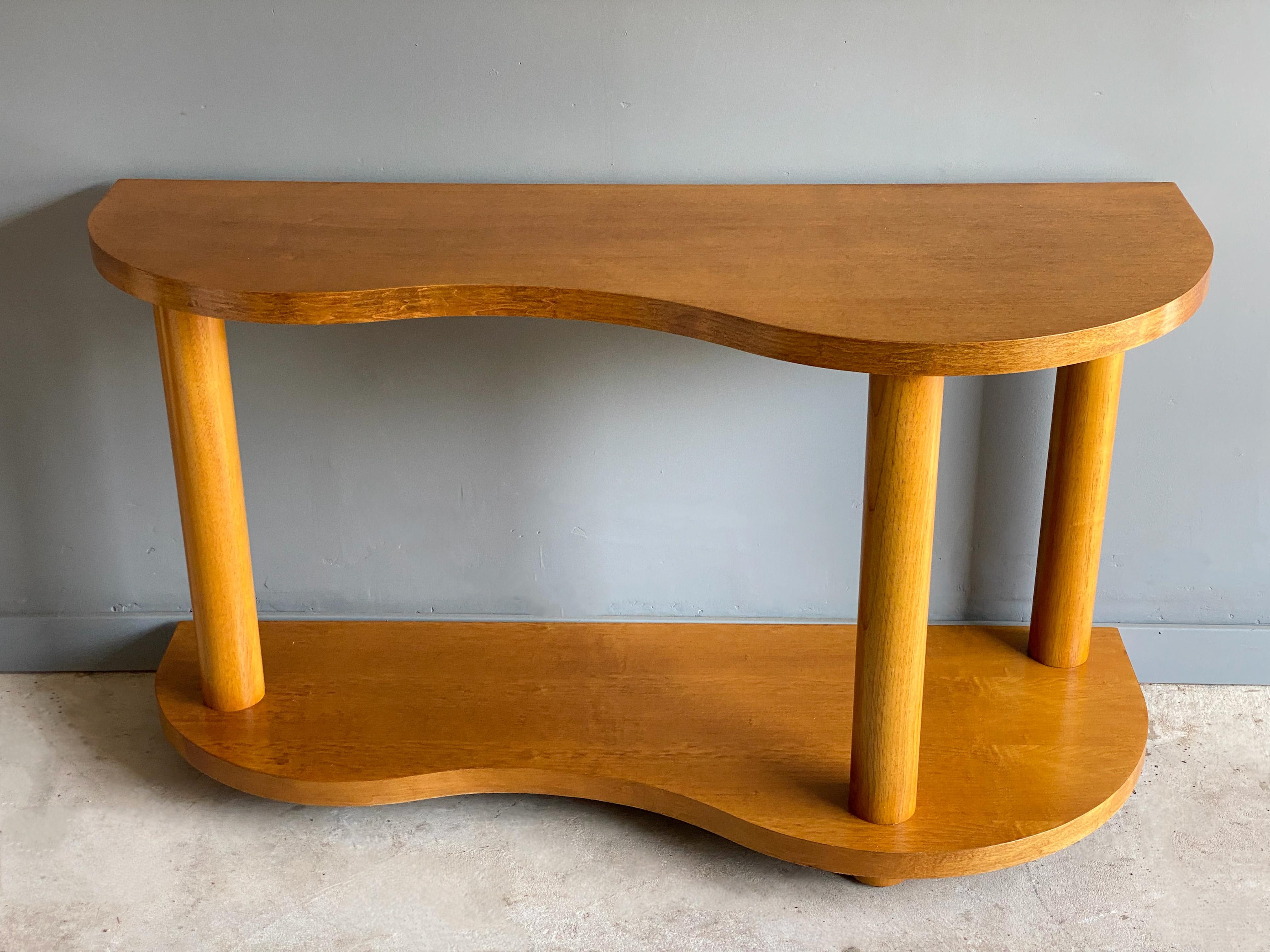 Organic form mid century console or sofa table in the style of Gilbert Rohde. Circa 1960s. Constructed of free form wood top with three round pillars - giving the design and architectural aesthetic.