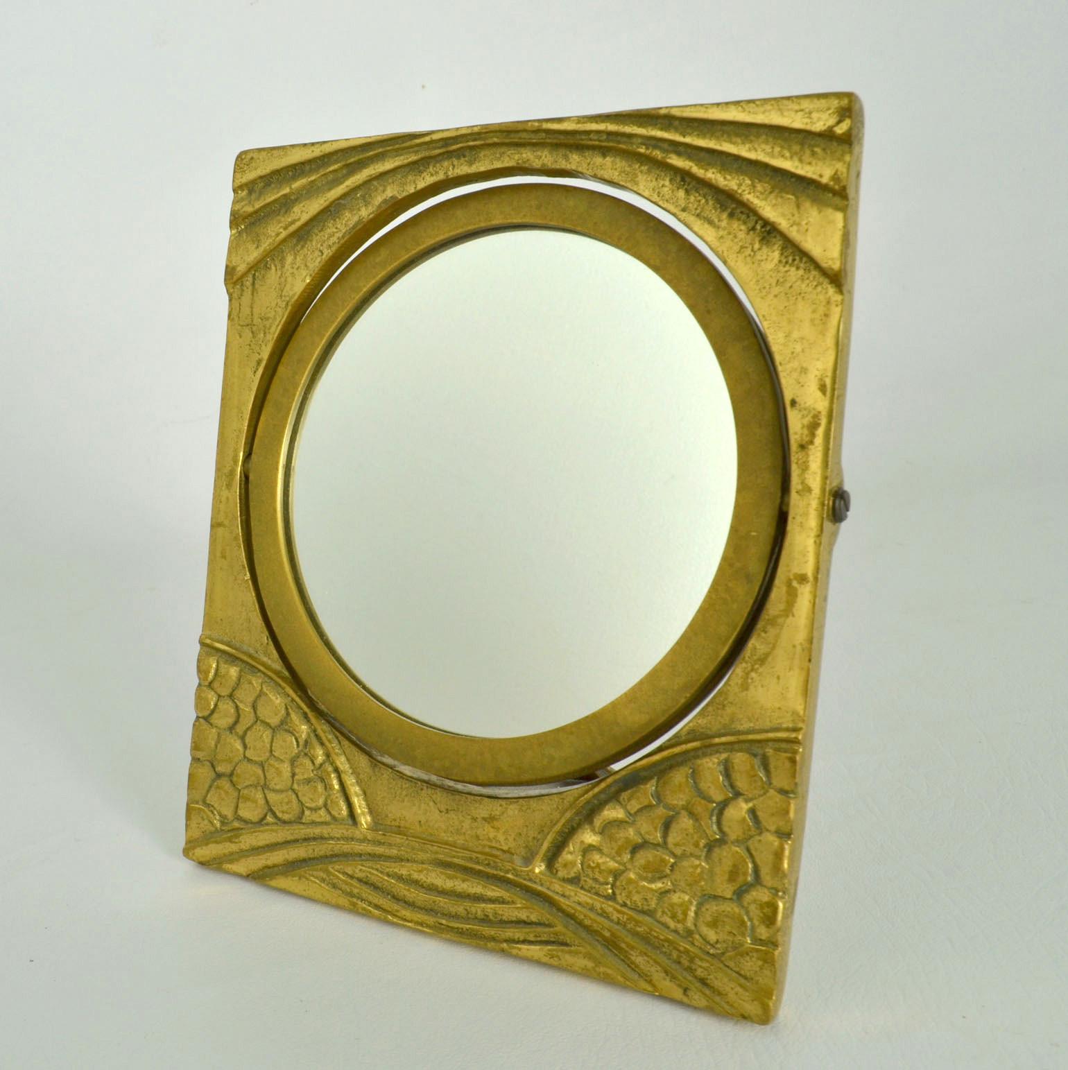 Organic table mirror pivots into a picture frame by touch. The bronze has been cast into a relief of natural lines inspired by Art Nouveau depicting a landscape and sunset. The frame and stand are cast in one piece and is angled for an improved