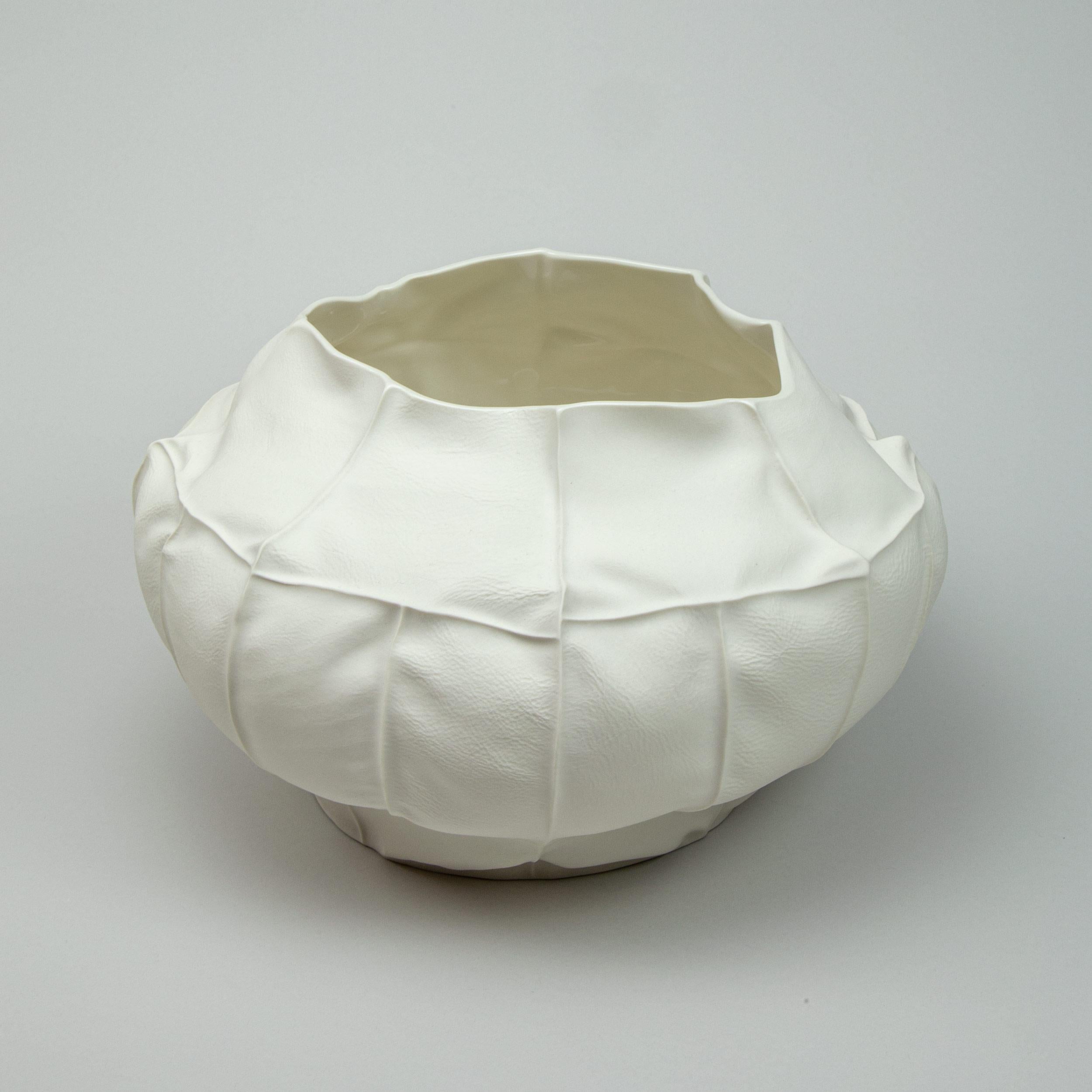 A large porcelain vessel with leather textured exterior surface and clear glazed interior. As a result of the production process each item is one-of-a-kind. 

A multitude of small leather panels are sewn together to create the leather mold for the