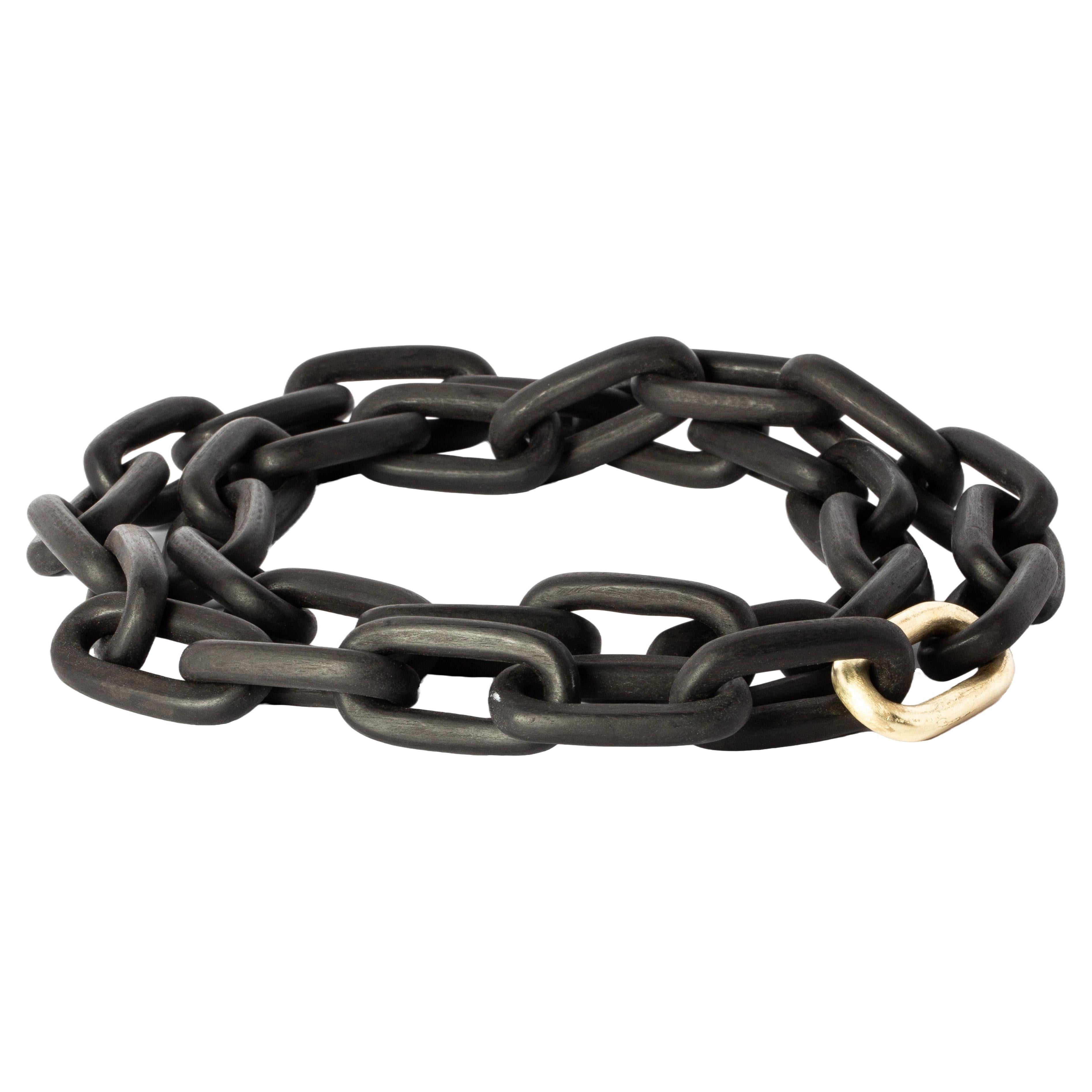 Chain necklace made of blackwood with gold plated brass clasp. All organic chain is carved by hand. In the case of the chains made of wood, they are absolutely seamless; carved from a single long slab of wood (see link). 
The Charm System is an