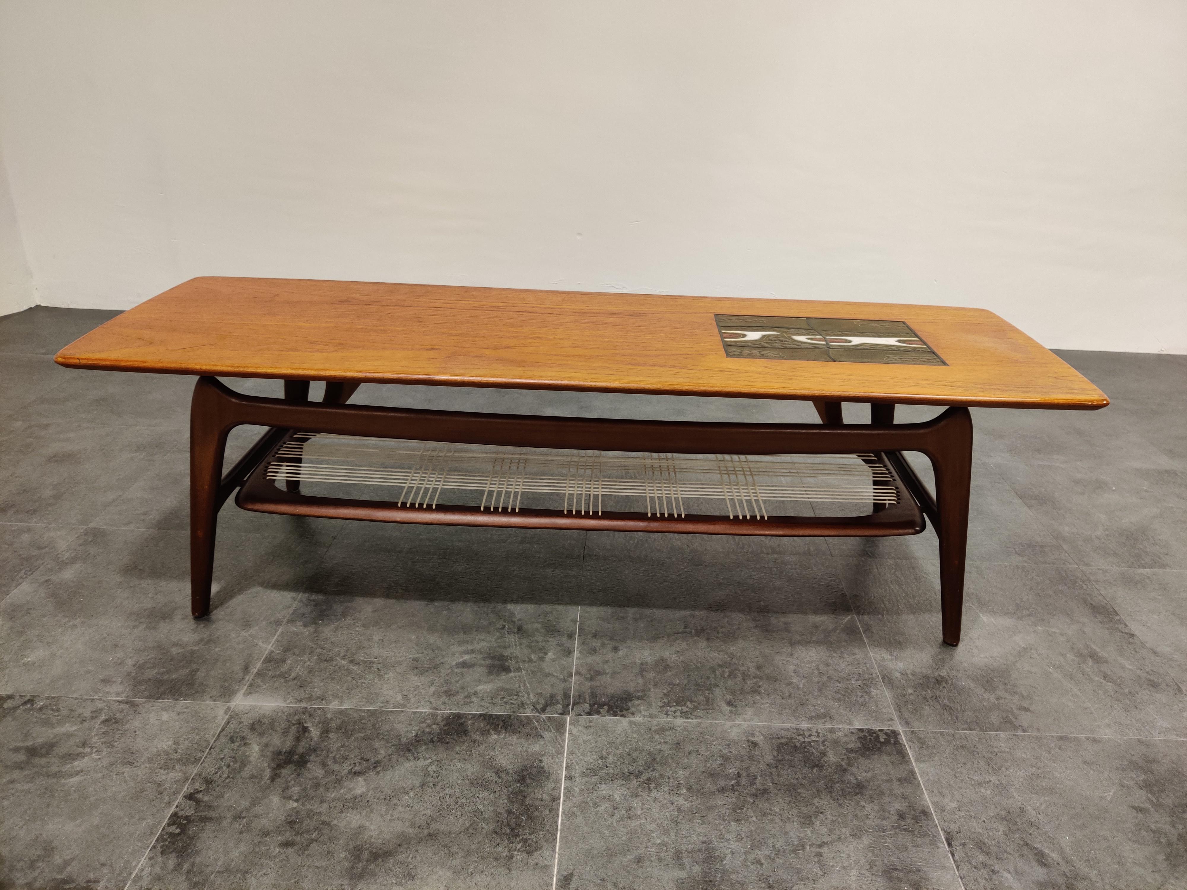 This organic coffee table was designed by Louis Van Teeffelen and manufactured by WEBE Meubel in the 1950s.

The table is made of teak, with ceramic details on the top designed by ceramist J. Ravelli. Cord webbing to store magazines.

Minor