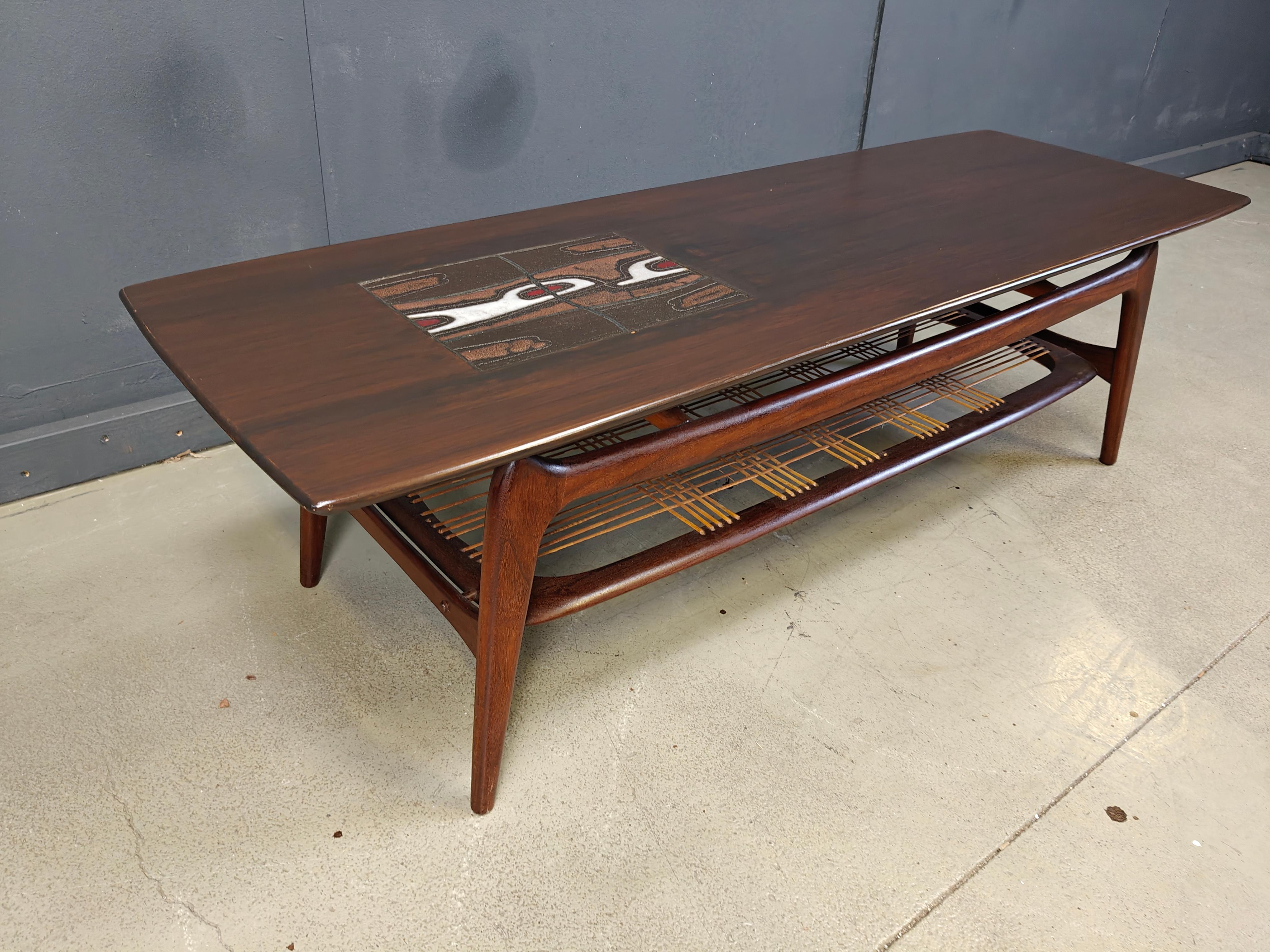 Cette table basse organique a été conçue par Louis Van Teeffelen et fabriquée par WEBE Meubel dans les années 1950.

La table est en teck, avec des détails en céramique sur le plateau, conçus par le céramiste J. Ravelli. Sangle en corde pour ranger