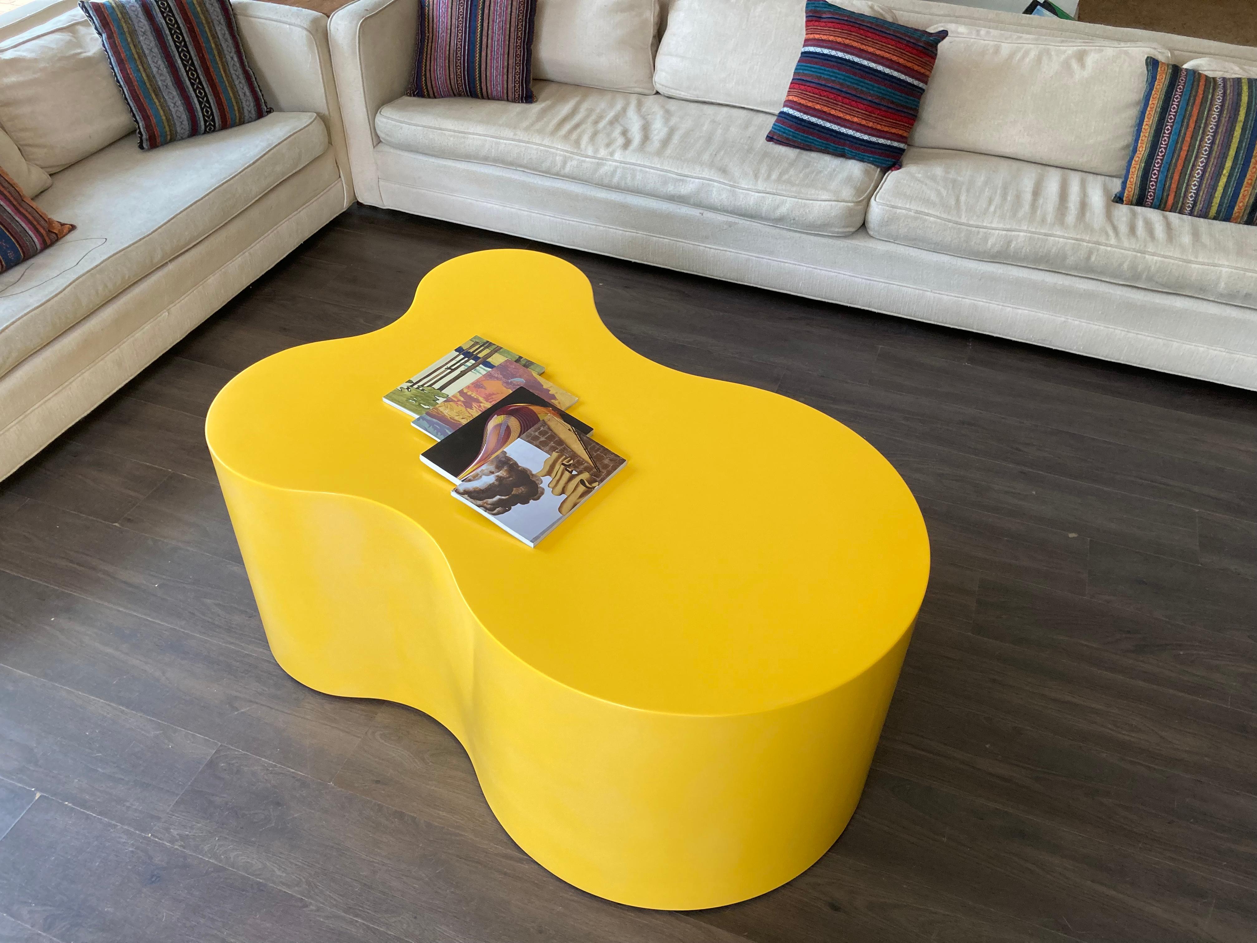 Cool Table basse organique faite de contreplaqué et de bois avec une finition de peinture jaune. La table est équipée de quatre roulettes.