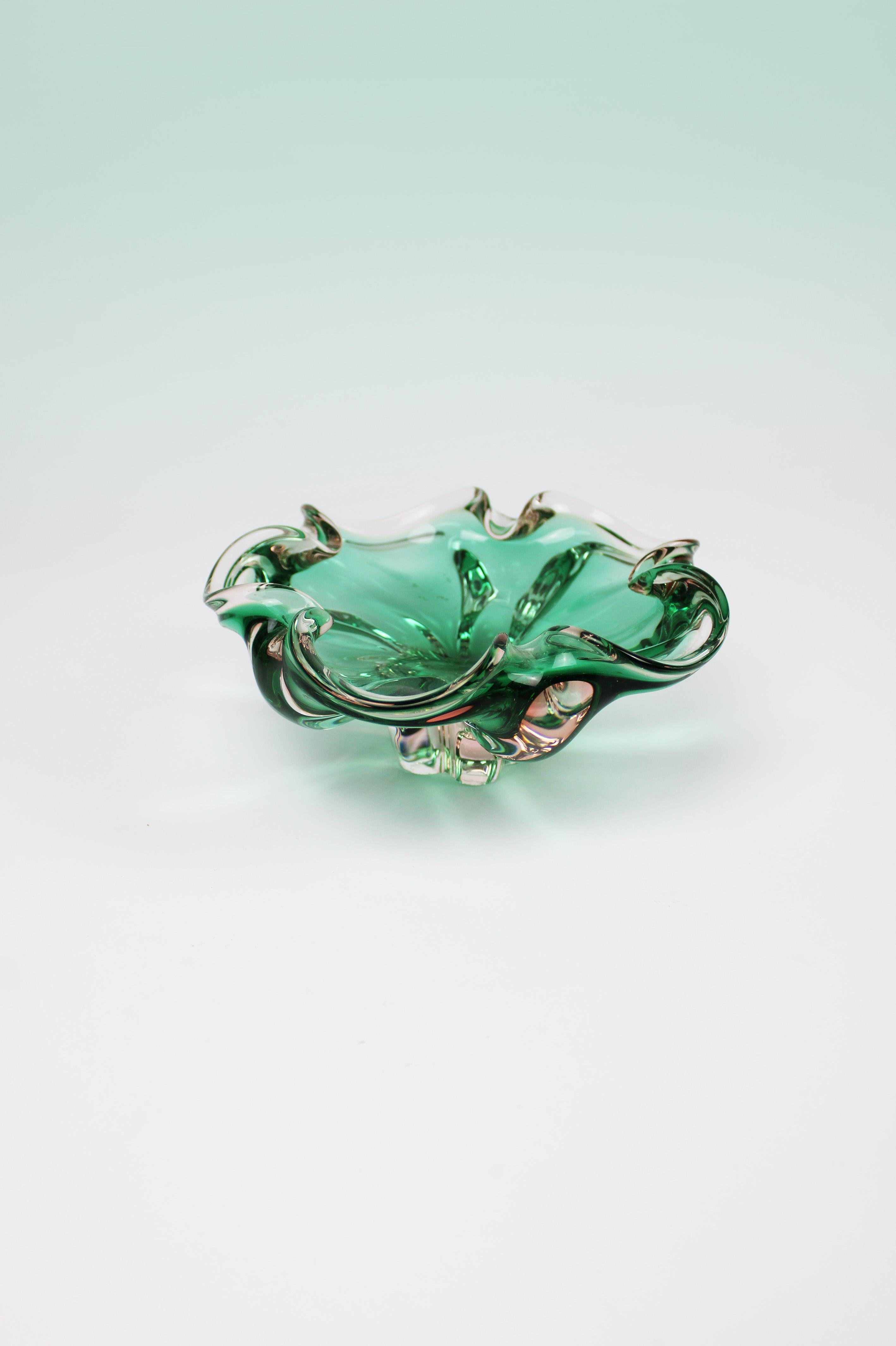 Ti presentiamo una splendida ciotola in cristallo organico della metà del XX secolo in Italia, esempio di raffinato artigianato di Murano. Questo pezzo di ispirazione floreale presenta un'accattivante tonalità verde-turchese, ottenuta grazie a