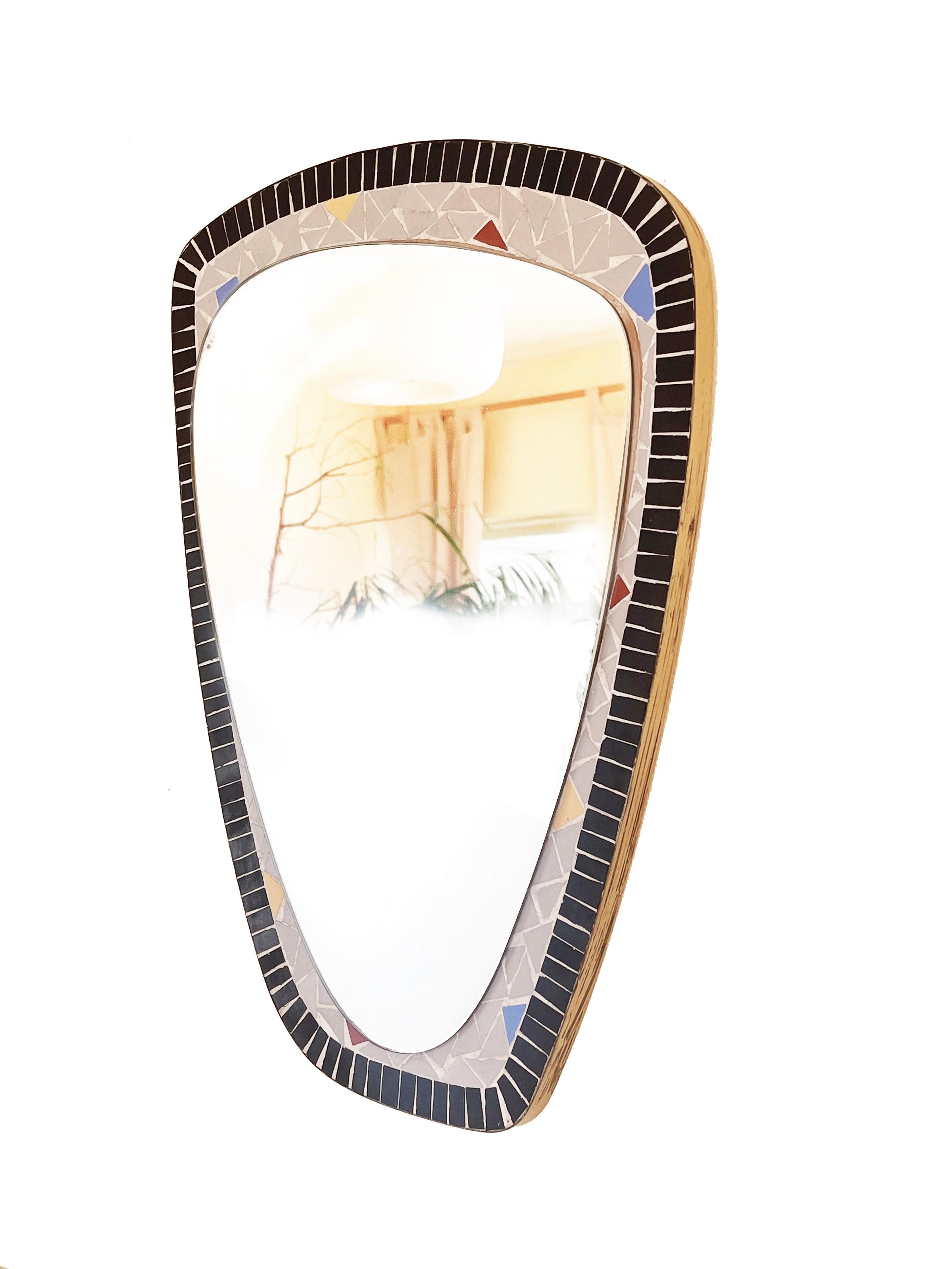 Specchio da parete di forma organica asimmetrica, scultoreo ed elegante di Berthold Müller.
Creato verso la fine degli anni '50 e l'inizio degli anni '60 in Germania.
Realizzato in mosaico nero opaco e grigio chiaro, un dettaglio divertente è