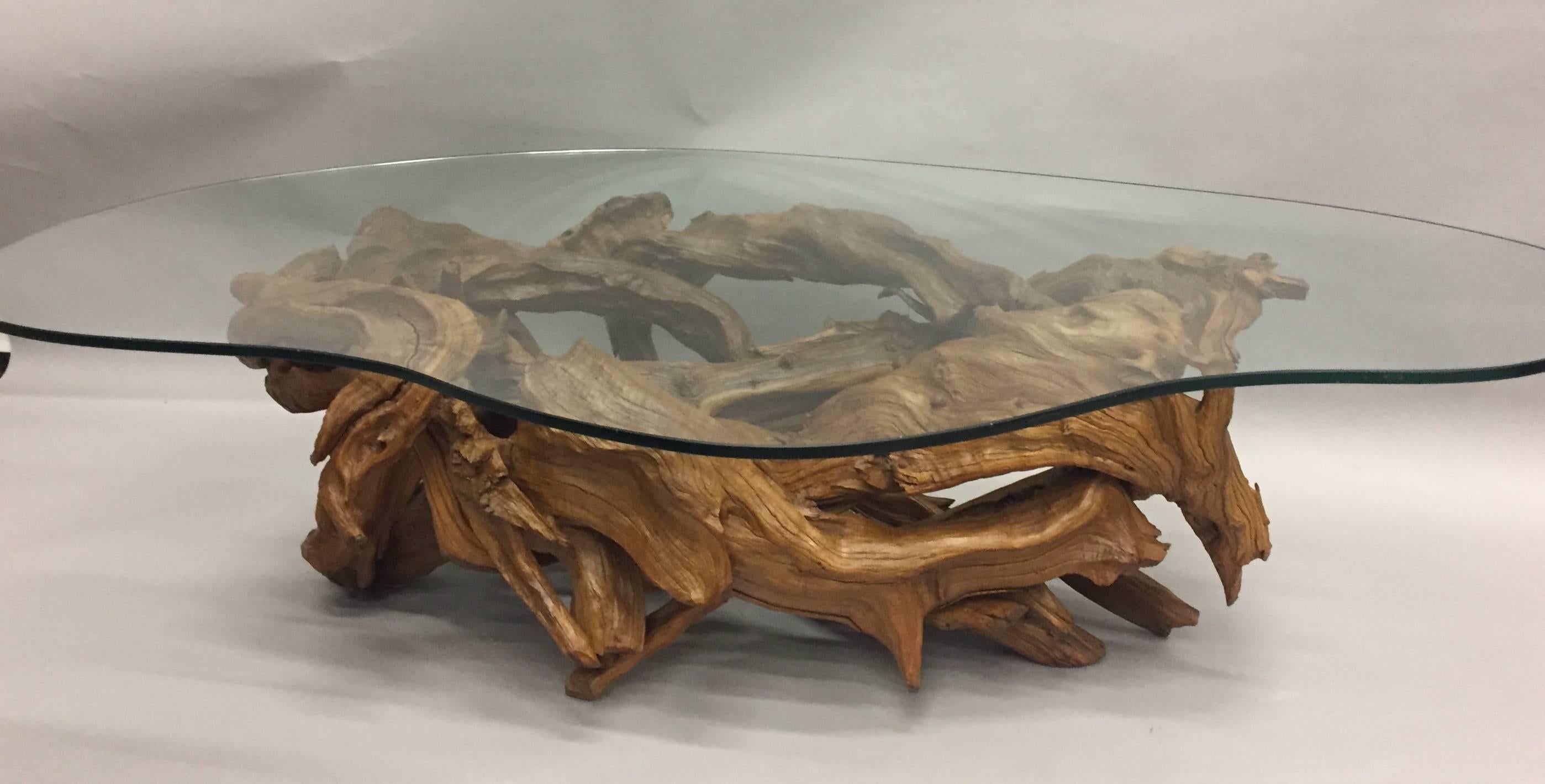 Stylish organic modern coffee table having a sculptural root wood base in a weathered light brown color, topped with an irregular amoeba shaped glass top.
Measures: Base 34.5 x 58.