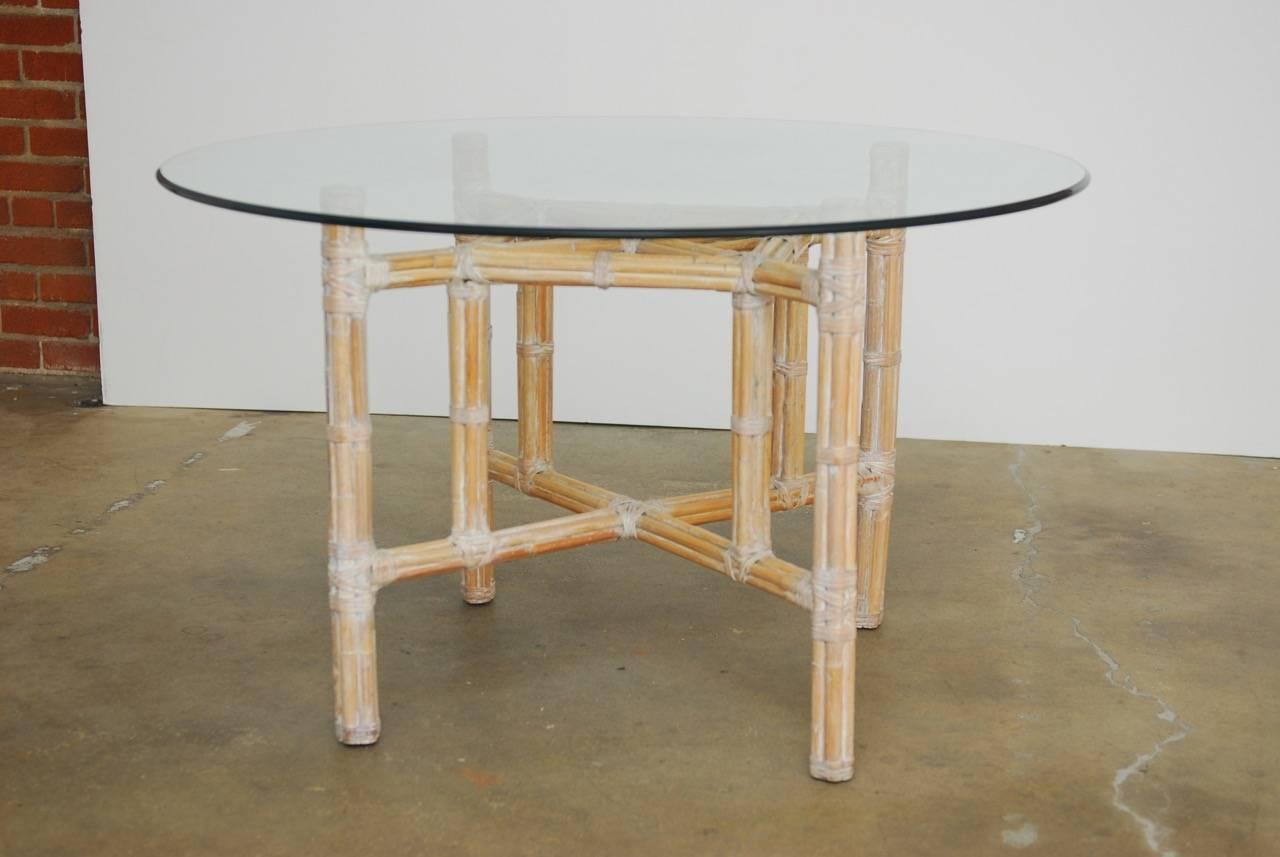 Round organic modern bamboo and rattan dining table by McGuire. Constructed from a bamboo wrapped metal skeleton and reinforced with McGuire's trademark leather rawhide strapping. The natural rattan has been finished with a whitewash and is topped