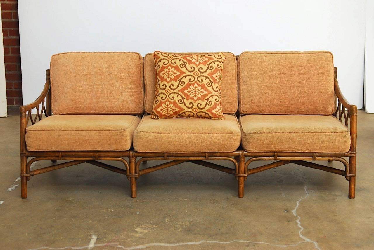 Organic modern sofa by Brown Jordan constructed from bamboo and rattan. Handsome frame finished in dark brown with decorative lattice arms. Topped with thick cushions upholstered in a chenille style fabric in a rose gold shade.