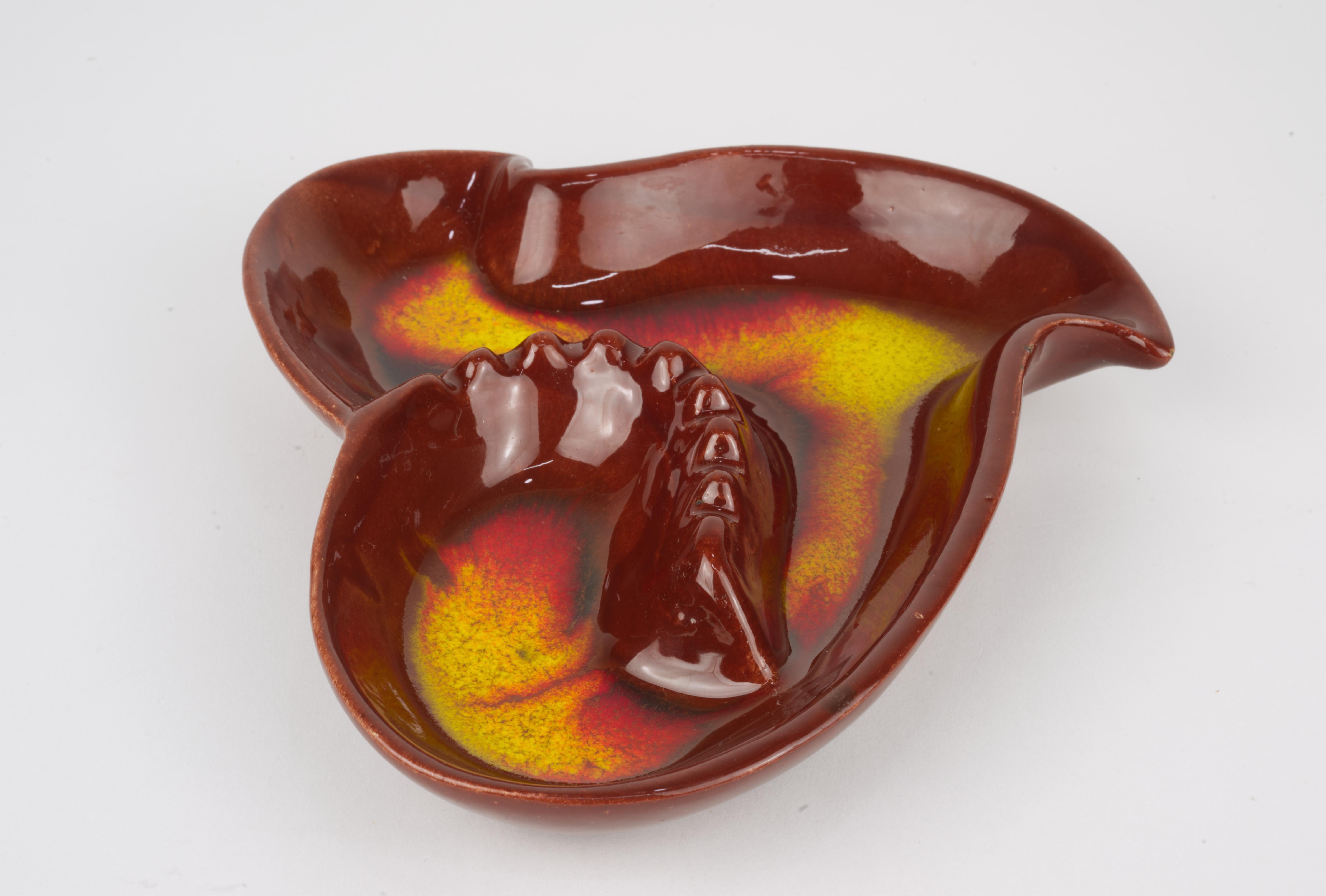  Large vintage ceramic ashtray in retro bright orange, red, and yellow colors was made by one of California art studio potteries in 1950s - 1960s. It has an organic, asymmetrical sculptural shape with smoke rest center.

The ashtray is signed on the