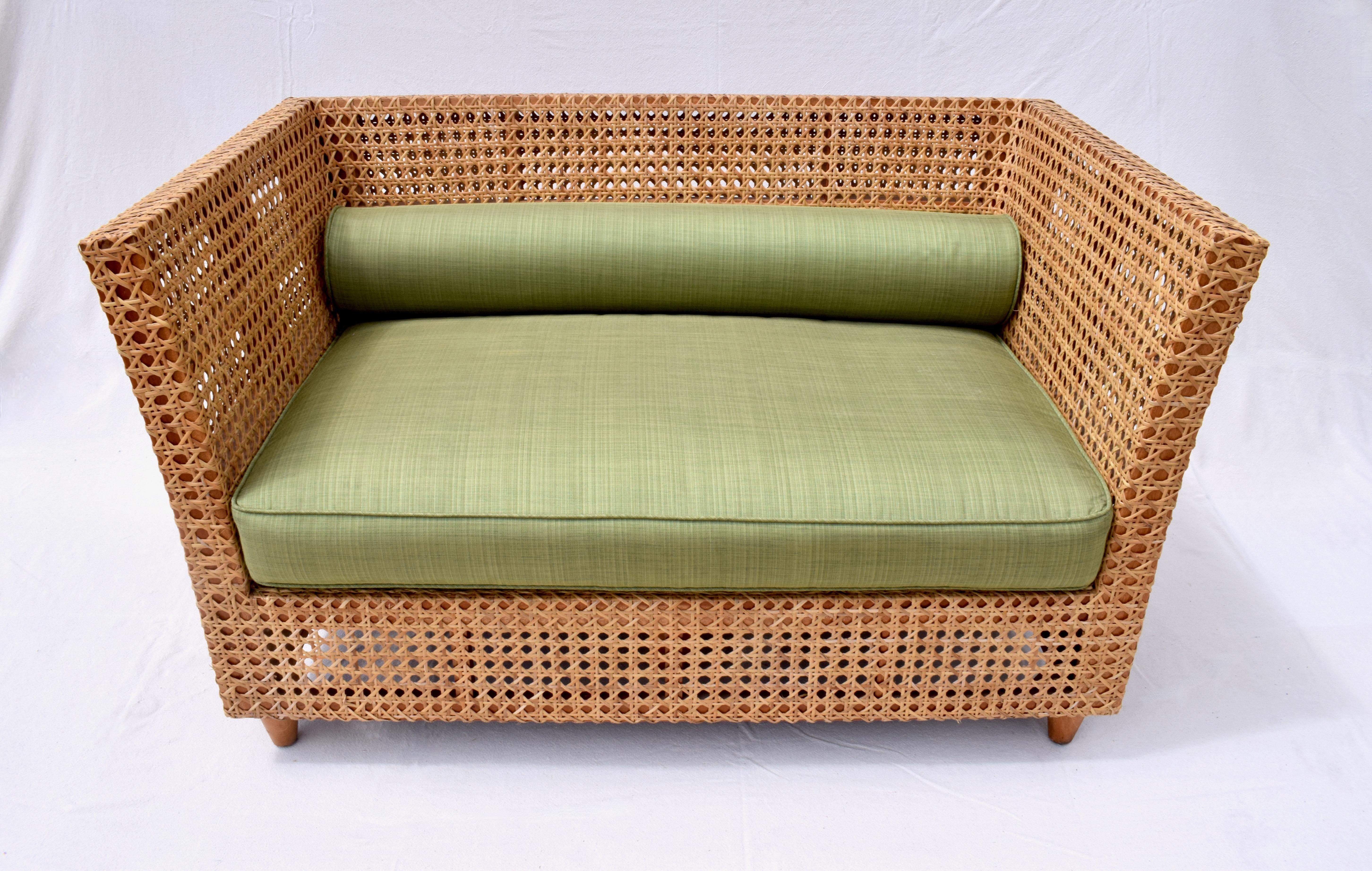 A solid Teak frame banquette settee with braided double cane work front & back newly upholstered in grass green Sunbrella fabric. Slightly splayed sides & wrap around cane portray the exquisite craftsmanship of this unique & substantial settee. Seat
