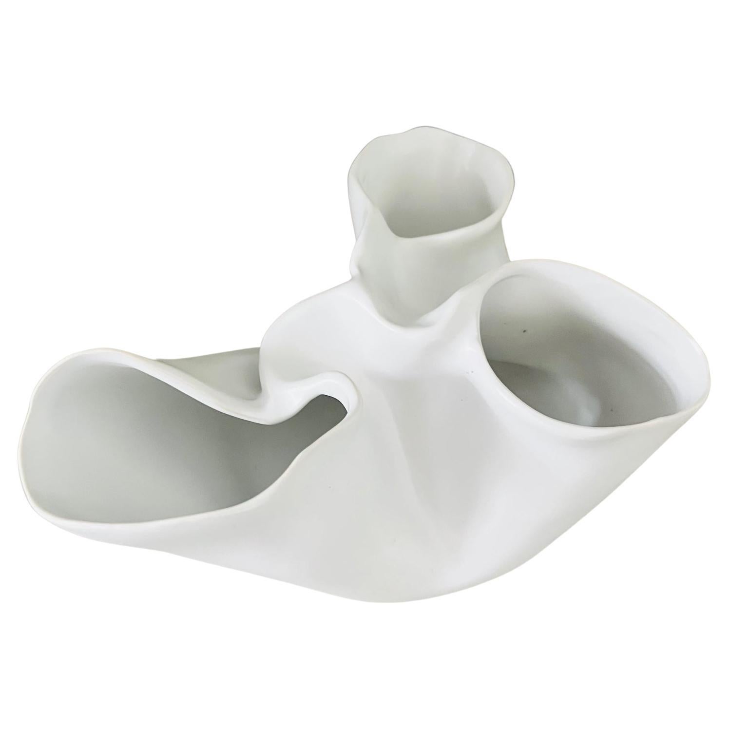 Zeitgenössische abstrakte niedrige Vase mit organischer Form, die an einen Herzmuskel mit Klappen erinnert. Die Porzellanvase hat eine mattweiße Oberfläche und kann als dekorative Schale oder als Objekt verwendet werden.