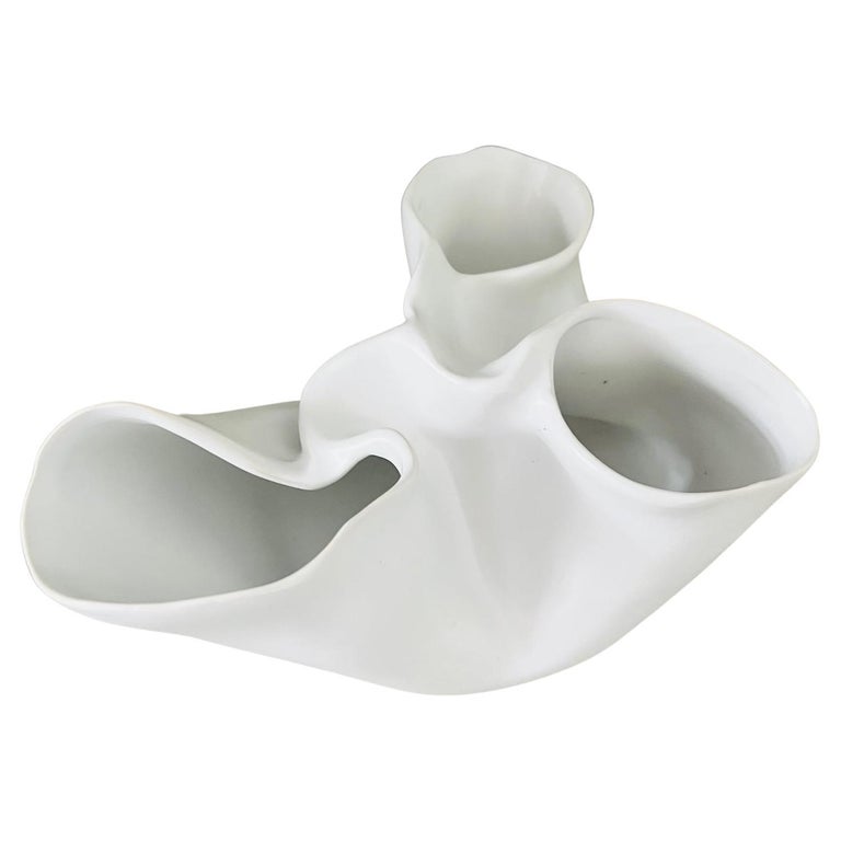 Contemporary abstract low vase with organic form reminiscent of a heart muscle with valves. The porcelain vase has a matte white finish and can be used as a decorative bowl or object.