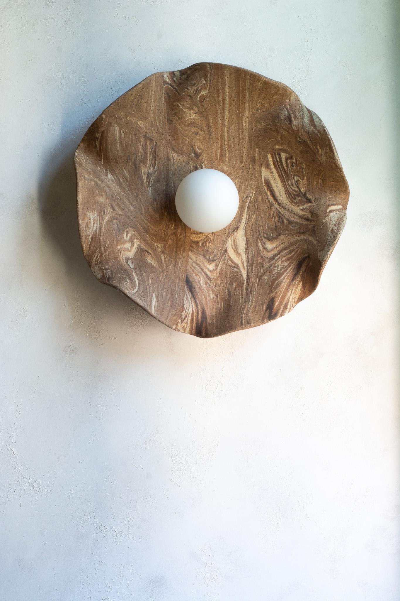 Funcional y escultural a la vez, este aplique de pared presenta un cautivador diseño orgánico y terroso. Se asemeja a una flor floreciente, pero también recuerda a las formaciones geológicas de las montañas.
Esculpida a mano a partir de múltiples
