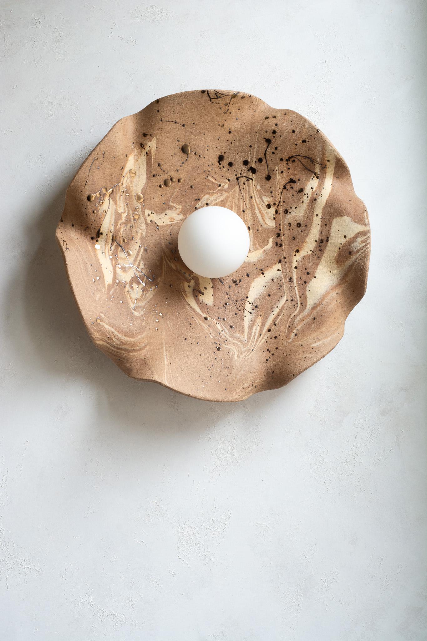 Funcional y escultural a la vez, este aplique de pared presenta un cautivador diseño orgánico y terroso. Se asemeja a una flor floreciente, pero también recuerda a las formaciones geológicas de las montañas.
Esculpida a mano a partir de múltiples