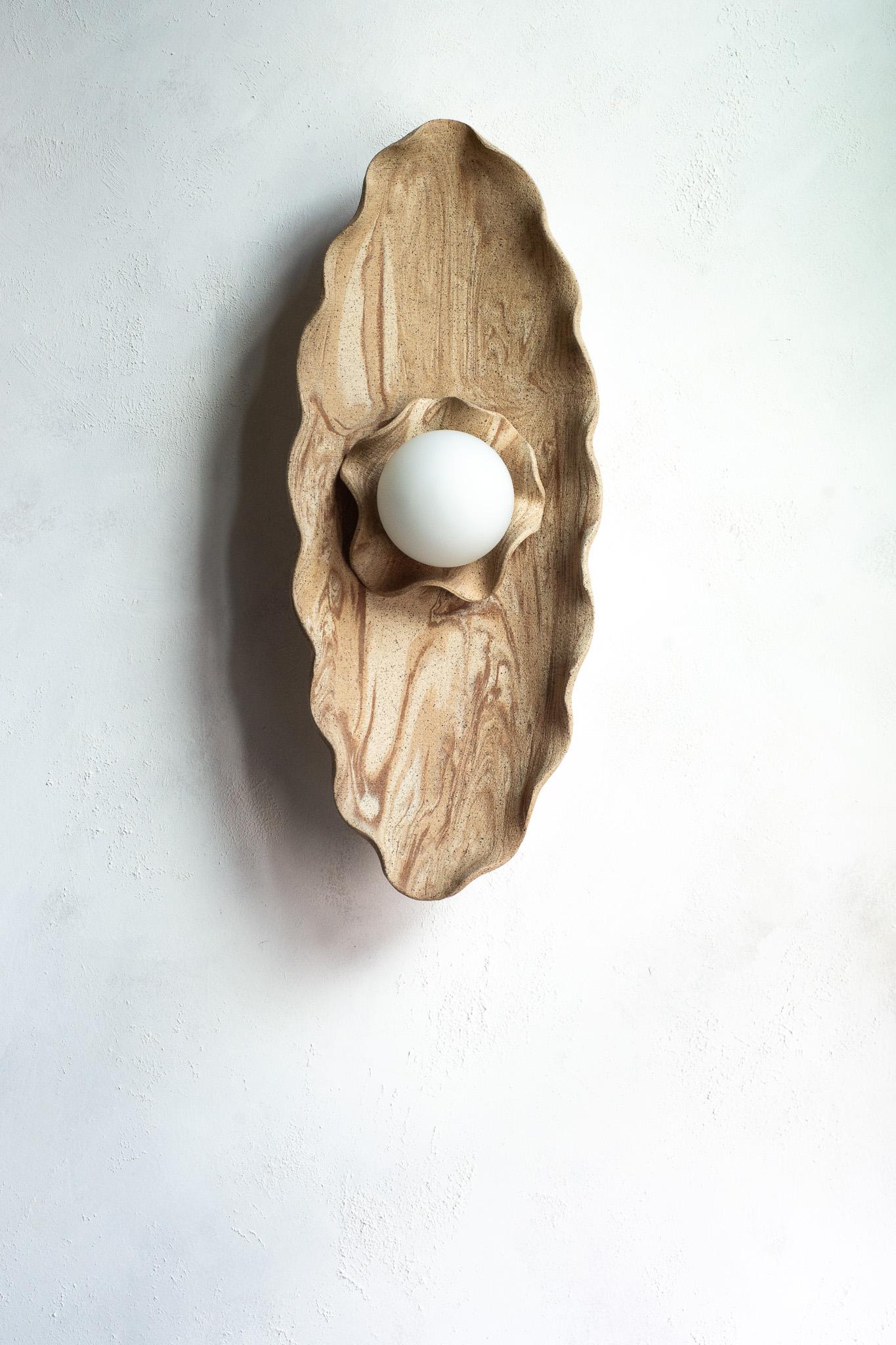 Funcional y escultural a la vez, este aplique de pared presenta un cautivador diseño orgánico y terroso. Se asemeja a una flor floreciente, pero también recuerda a las formaciones geológicas de las montañas.
Esculpida a mano a partir de múltiples