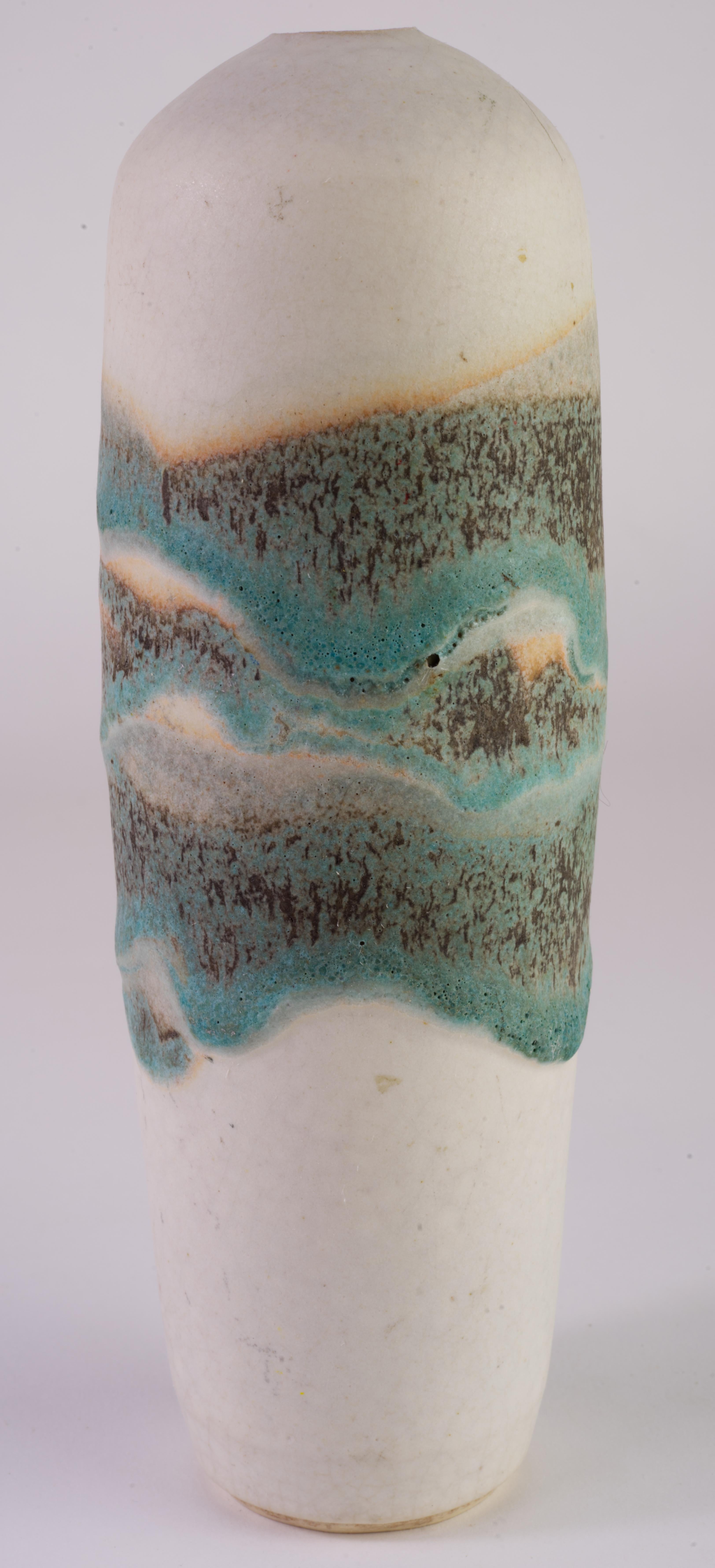 El jarrón cilíndrico moderno orgánico vintage con esmalte de lava turquesa y marrón sobre fondo crema mate fue hecho a mano por Charles Focht en su estudio de Tucson, Arizona. La paleta de colores procede del cobre de Arizona que se añade al
