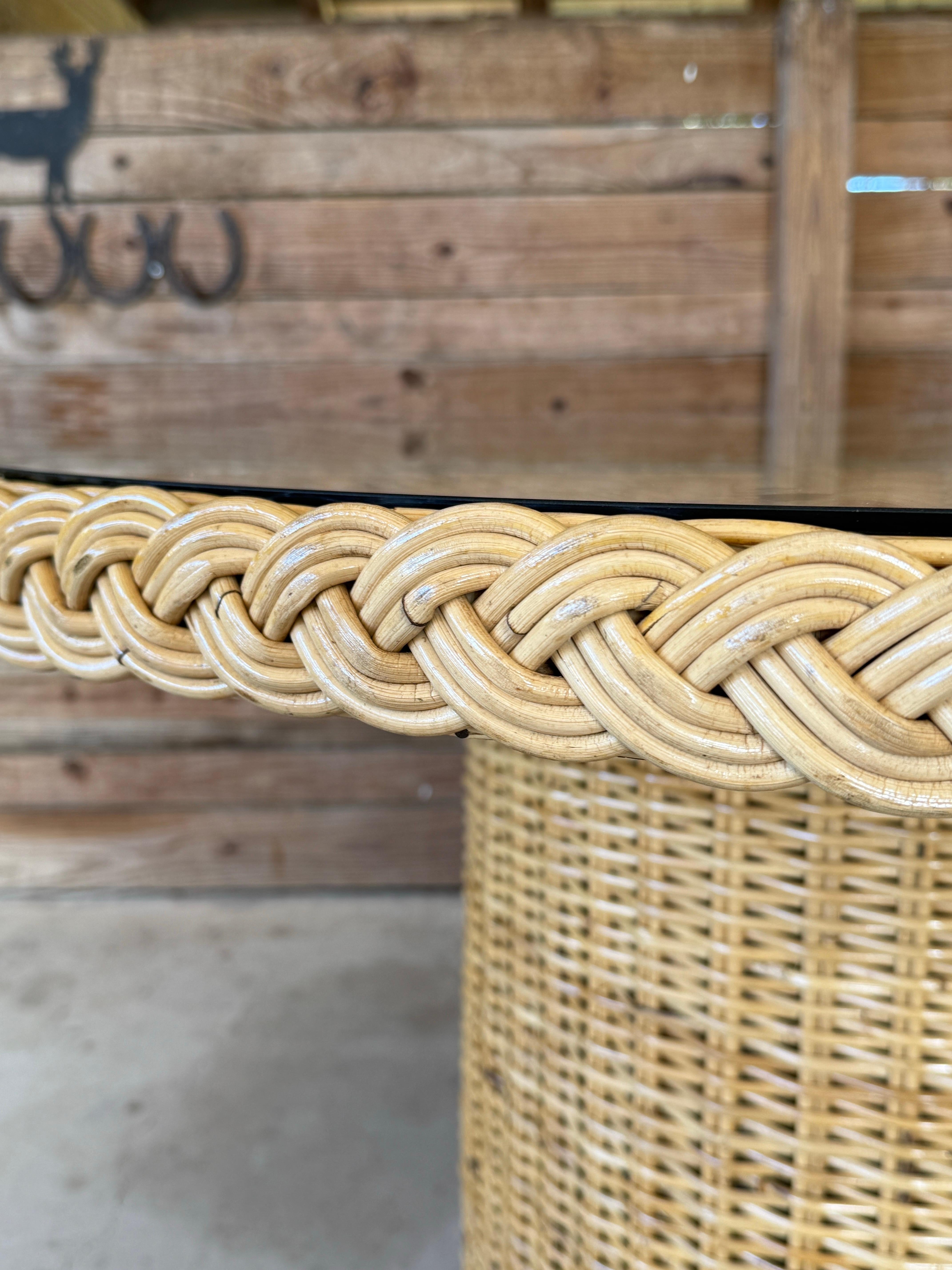 Elevate your dining space with this stunning rattan dining table by Wicker Works. Featuring a beautifully woven braid detail around the edge and a sturdy rattan base, this table is both elegant and functional.
The glass top provides a sleek surface