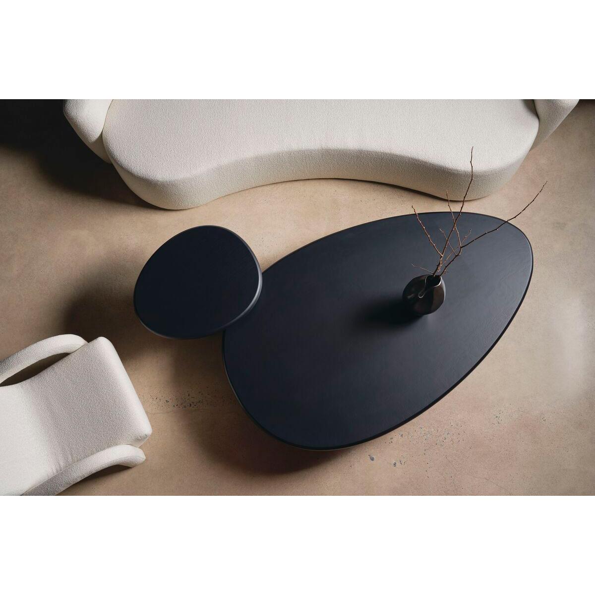 Effortless and organic, the table makes an elegant statement with its soft, pebble shape. Crafted from Tamo ash wood veneers in a dramatic dark coal finish, its fluid form features an expansive tabletop balanced on a uniquely shaped, asymmetrical
