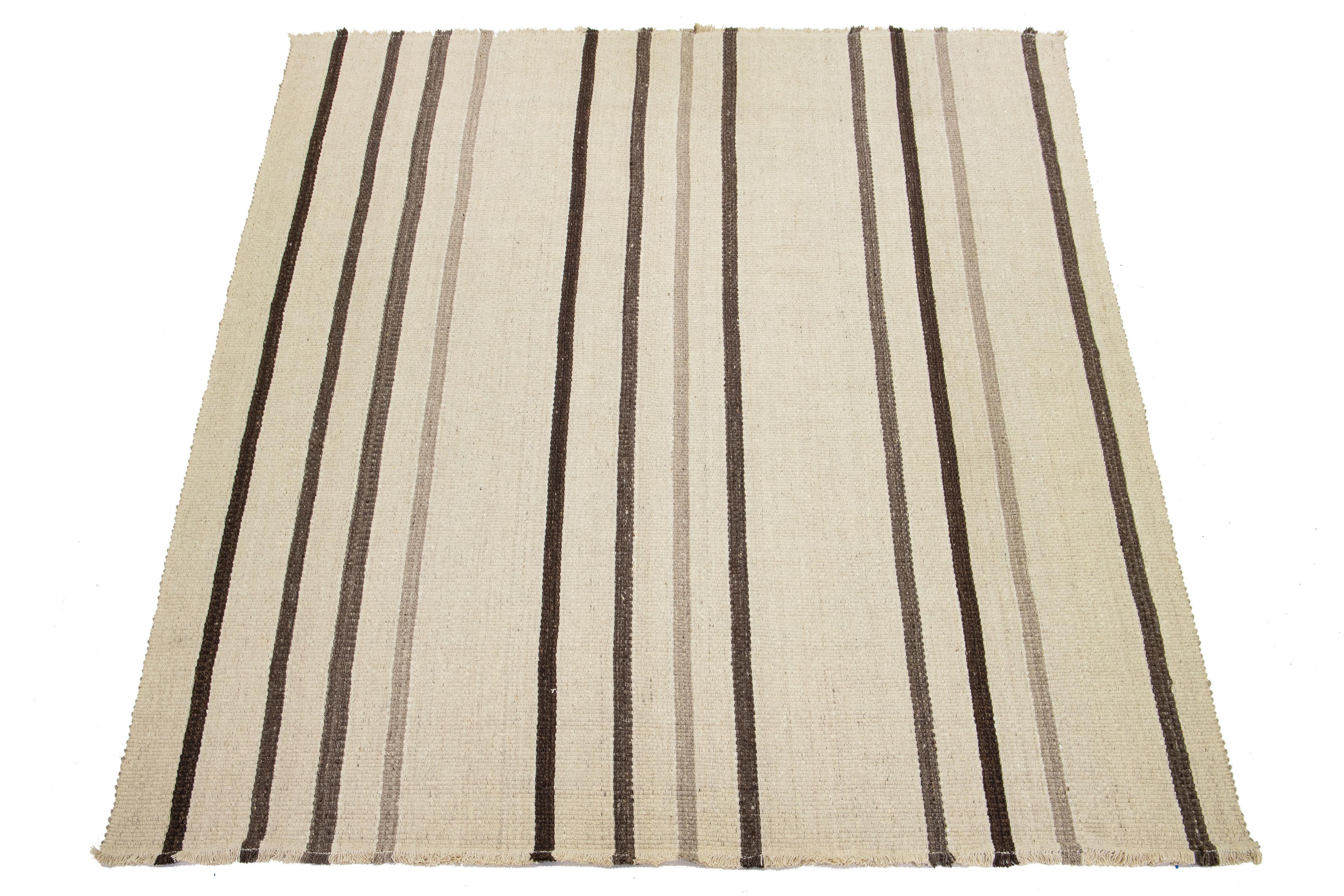 Dieser Teppich ist ein modernes Flachgewebe aus organischer Wolle mit Streifenmuster, das ein beige-braunes Grundmuster aufweist.

Dieser Teppich misst 12' x 15'2