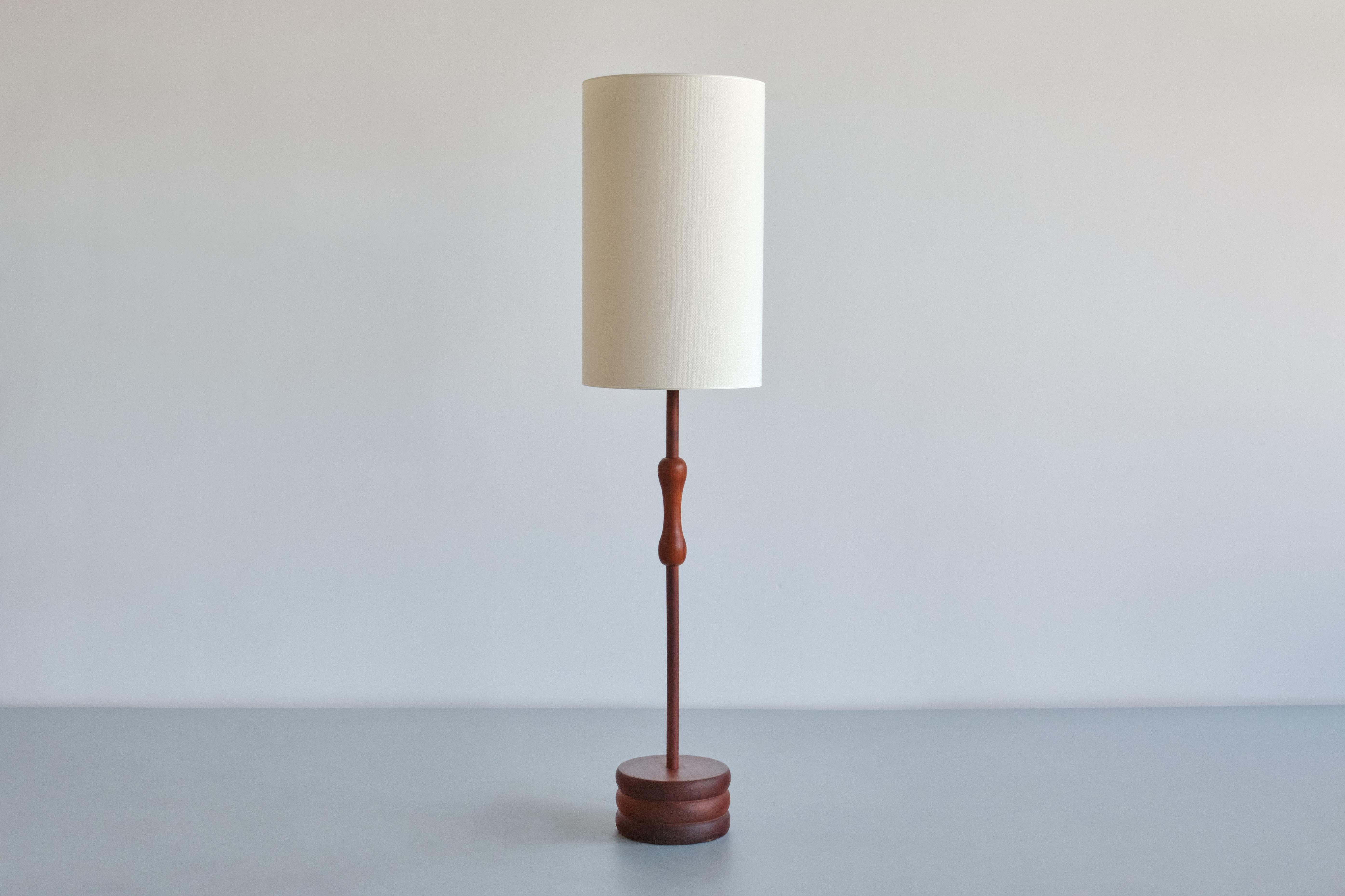 This striking floor lamp was produced in Sweden in the late 1950s.
The design consists of a circular base in solid teak wood with three carved, disc shaped circles. The central stem is again in solid teak wood and has a 
rounded, organic handle