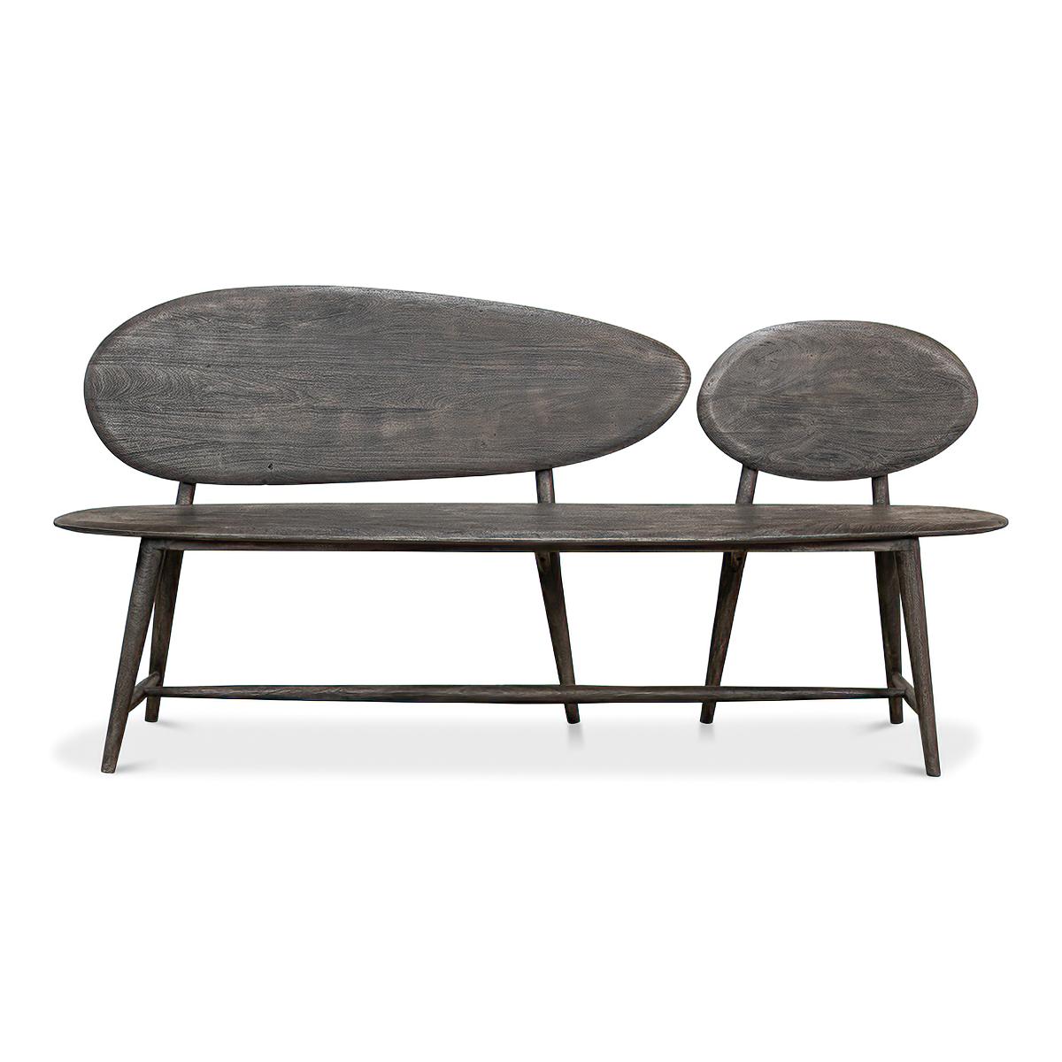 An organic modern greyed wood bench. This bench has a flair for the arts and is inspired by boulders and pebbles found in natural landscapes. It is hand-crafted and carved out of solid acacia and has a natural finish. Its unique abstract design
