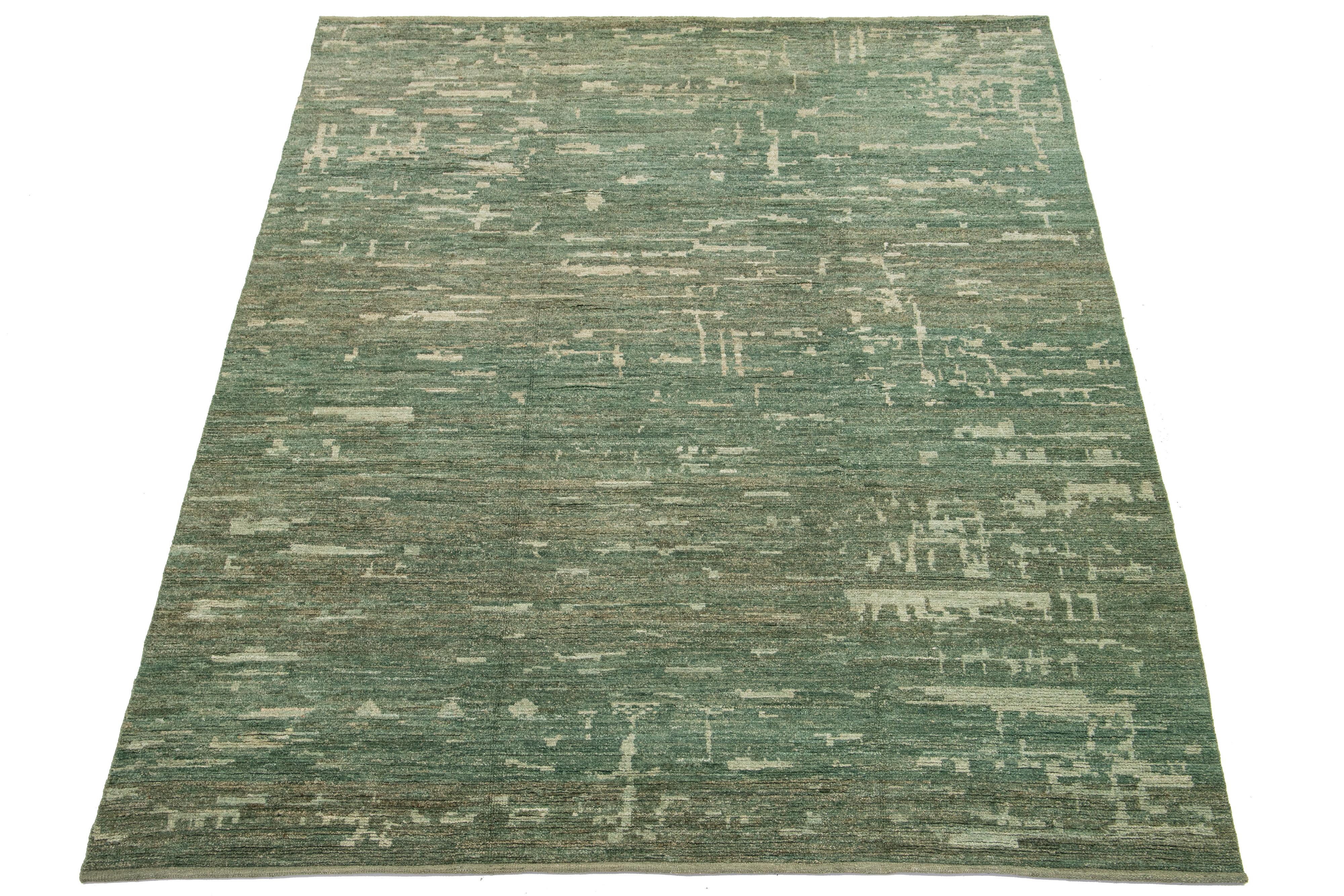 This exceptional hand-knotted oversized organic Moroccan wool rug commands attention with its vibrant green background, beautifully complemented by beige accents and striking abstract designs. It is truly a stunning centerpiece that elevates the