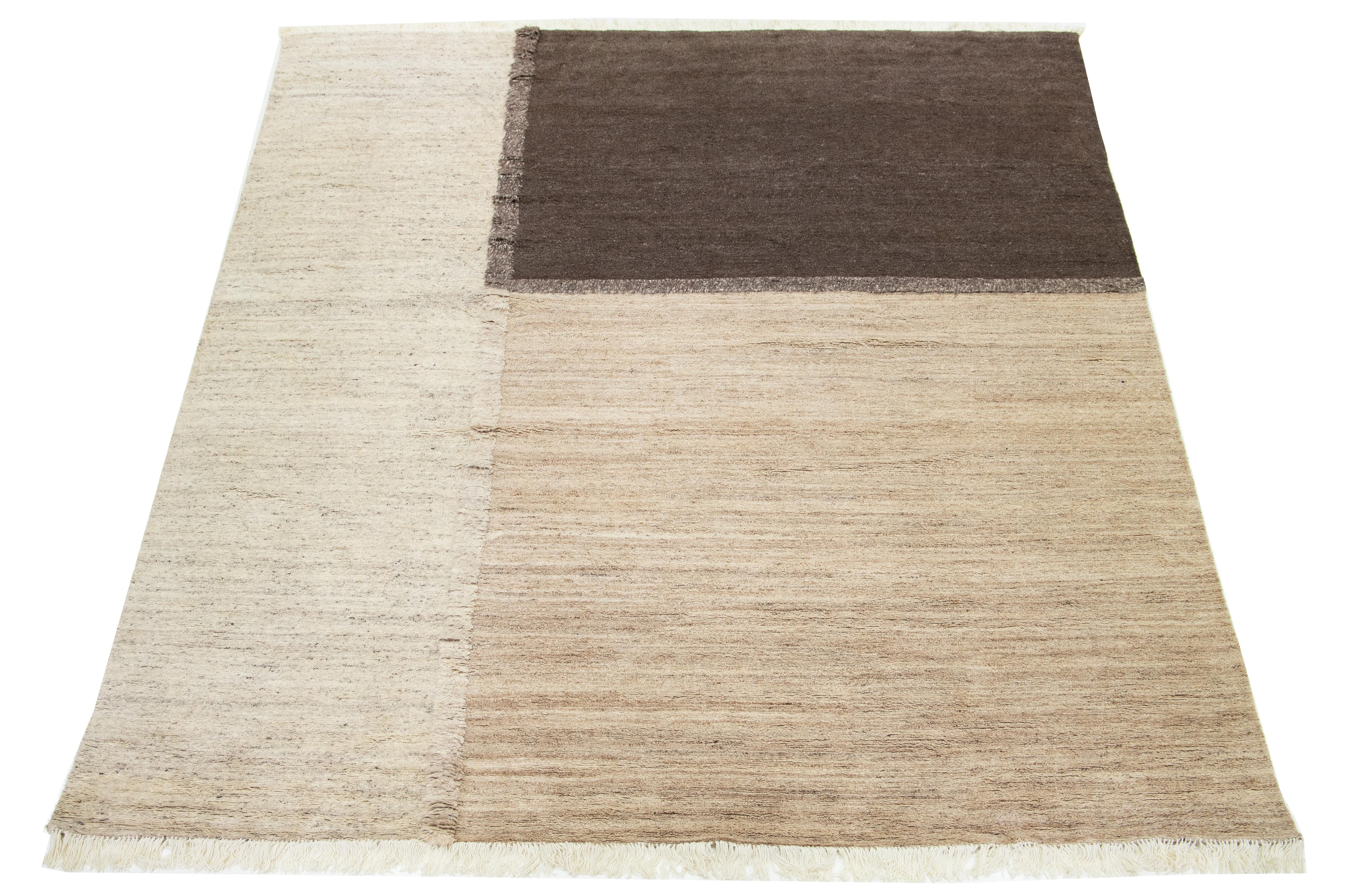 This exquisite hand-knotted Moroccan wool rug features a beige field with a brown geometric design and fringes, making it a captivating centerpiece for any room.

This rug measures 12'2
