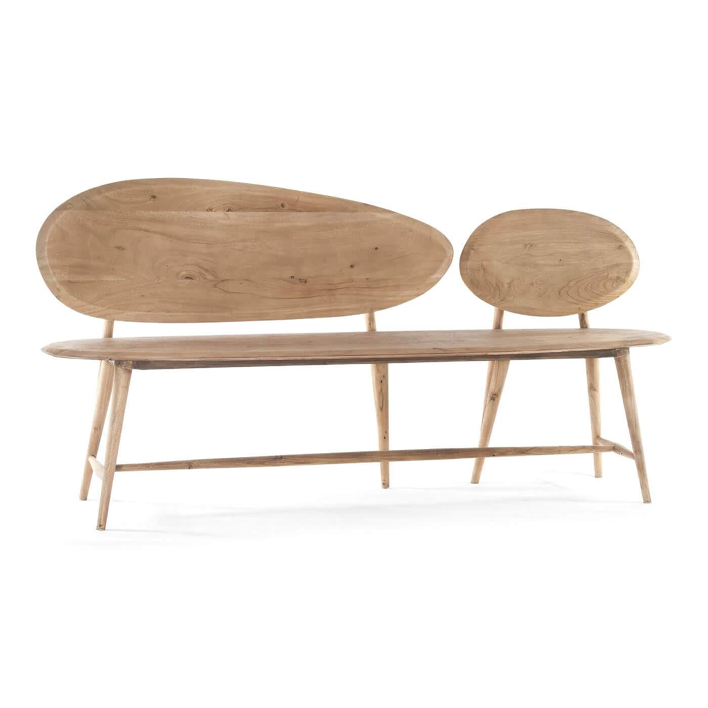 An organic modern natural wood bench. This bench has a flair for the arts and is inspired by boulders and pebbles found in natural landscapes. It is hand-crafted and carved out of solid acacia and has a natural finish. Its unique abstract design