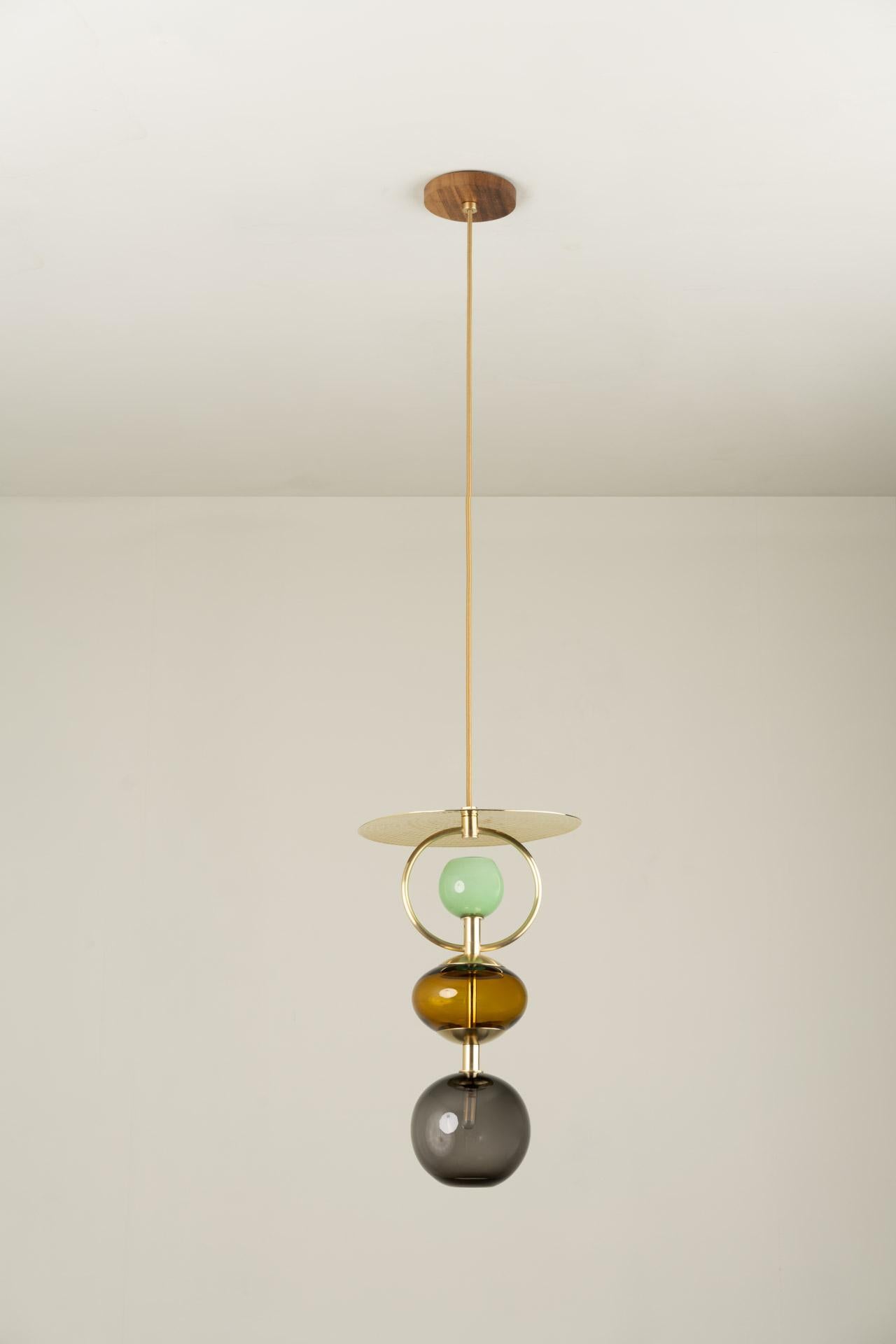 VITRA (AMBER) pendant light was designed for the Atomic collection by Mexican artist Isabel Moncada.

The fascination produced by the light through the colors of the glass, the curved silhouette, and the hand-forged brass are the elements that come
