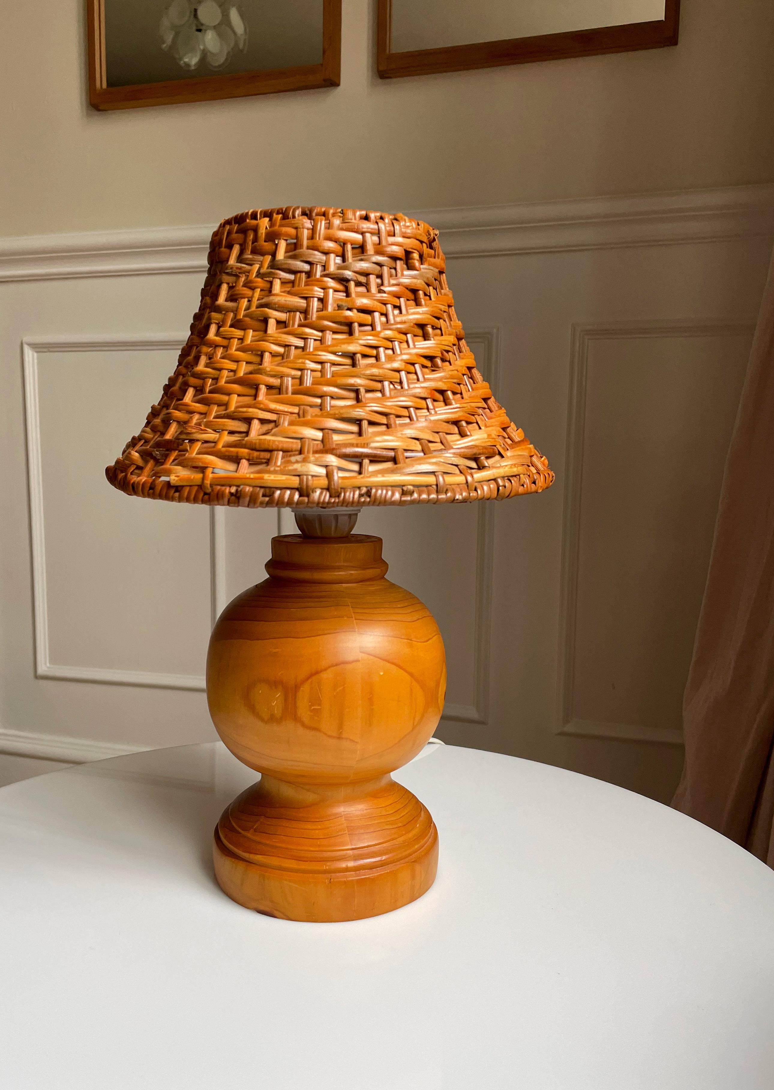 Vintage lacquered pine wood soft shaped table lamp with original braided rattan shade. White cord with switch. E27 bulb. Beautiful vintage condition. 
Sweden, 1979.