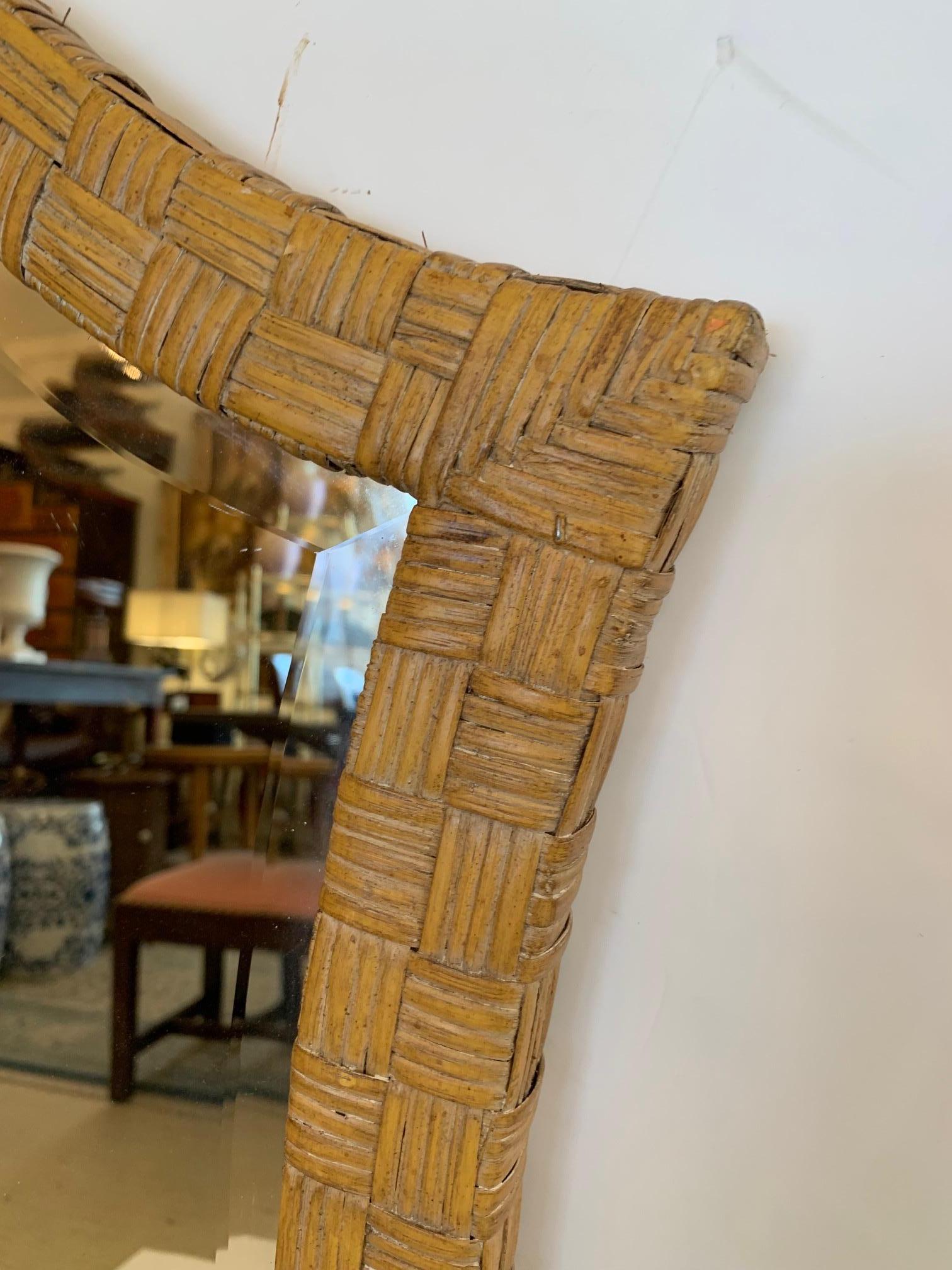 Superbe miroir moderne organique en rotin et bambou ayant une forme allongée inspirée des trous de serrure.