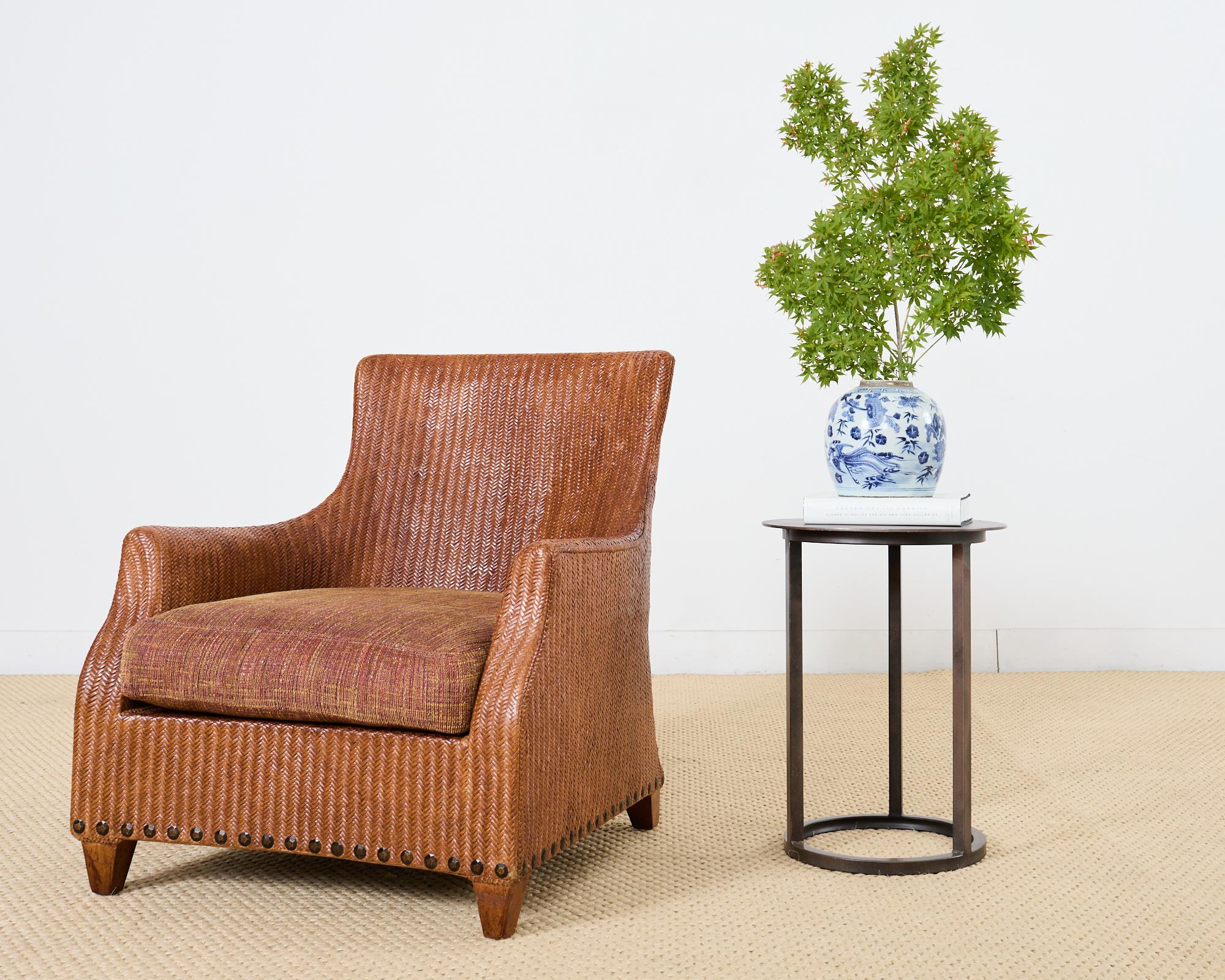 Handsome woven rattan wicker lounge chair or armchair made in the coastal organic modern style by Lane Venture. The chair has a large wood frame with an ergonomic curved back that gracefully slopes down to the arms measuring 24 inches high. The