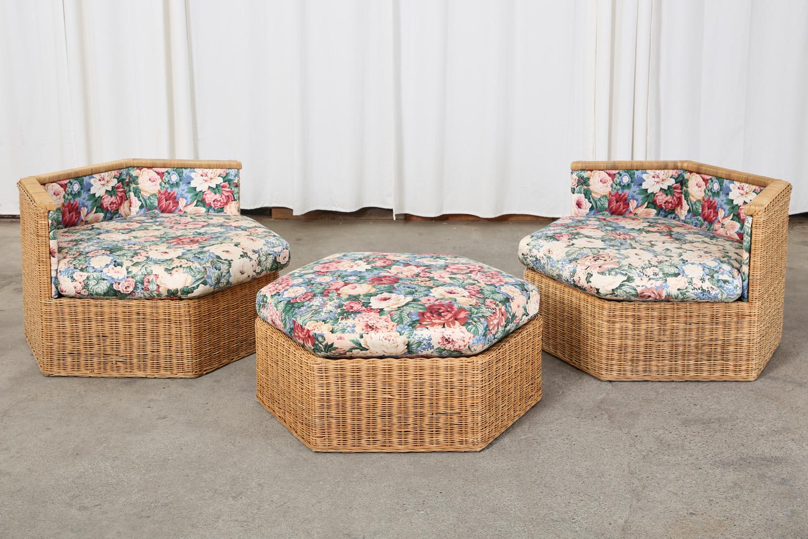Stylish organic modern modular seating sofa set or suite consisting of two hexagonal shaped lounge chairs and a conforming ottoman. Constructed from wood frames covered with woven rattan wicker. Topped with loose seat cushions and padded upholstery