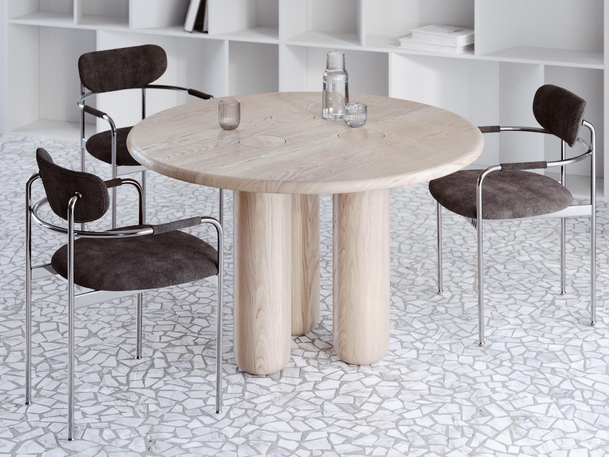 This dining table is crafted from solid oak with a refined whitewashed finish that softens the natural grain and gives the piece a fresh, contemporary character. Designed in an organic modern style, it features flowing lines and rounded forms that