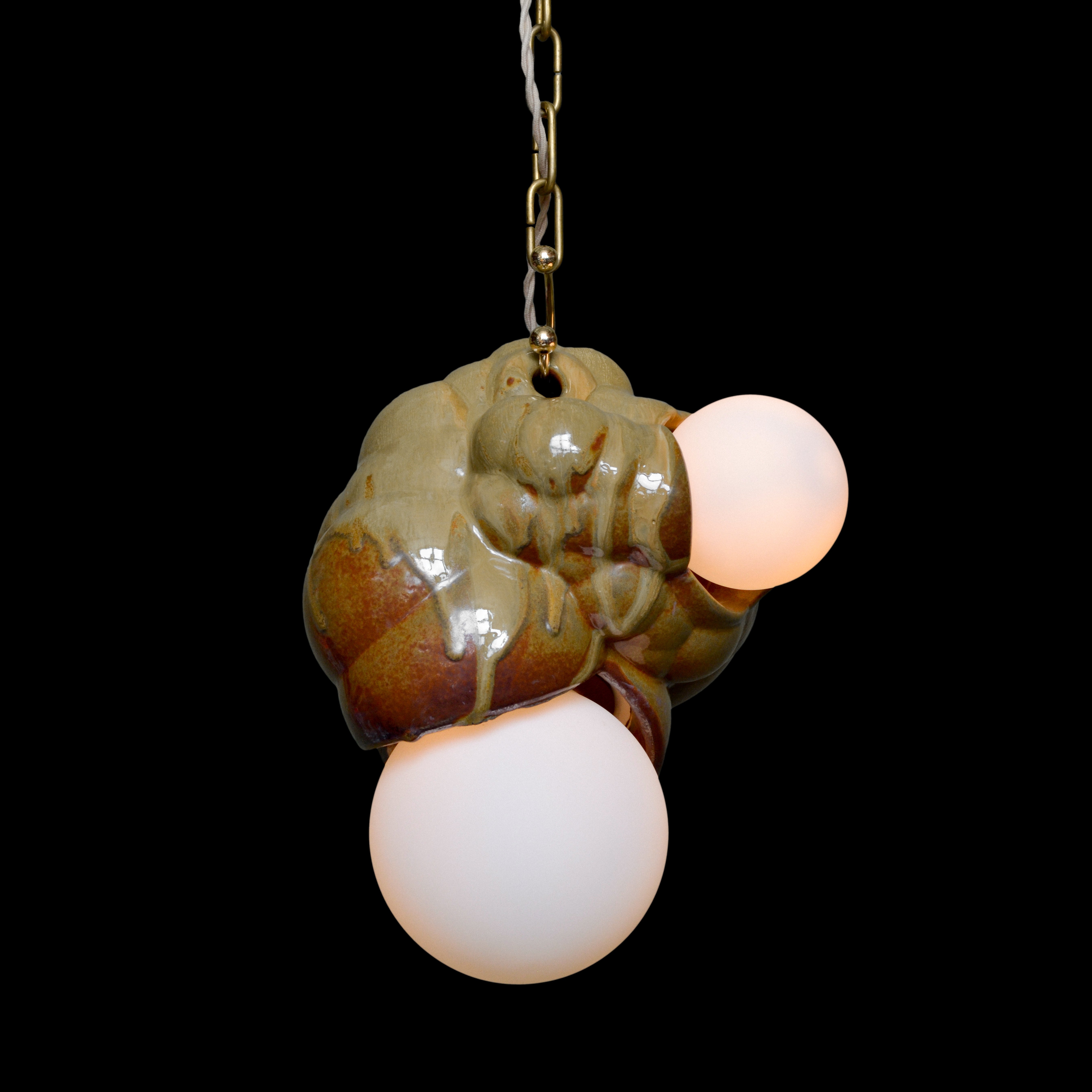Capullo Pendant is a handcrafted ceramic pendant featuring two mouth-blown glass globes, inspired by the cocoon structures of insects as the name “Capullo” reflects. The unique hanging ring resembles a piercing, accentuating the organic and fleshy
