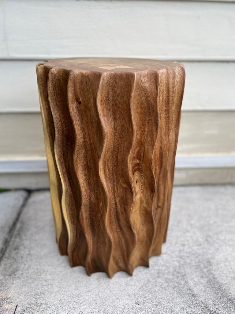 Organic Modern sculptural side table with fluted design. This versatile piece can also be used as a stool or a pedestal. Comprised of reclaimed suar wood, the table features hand carved fluted sides with wave formation. Each table is uniquely