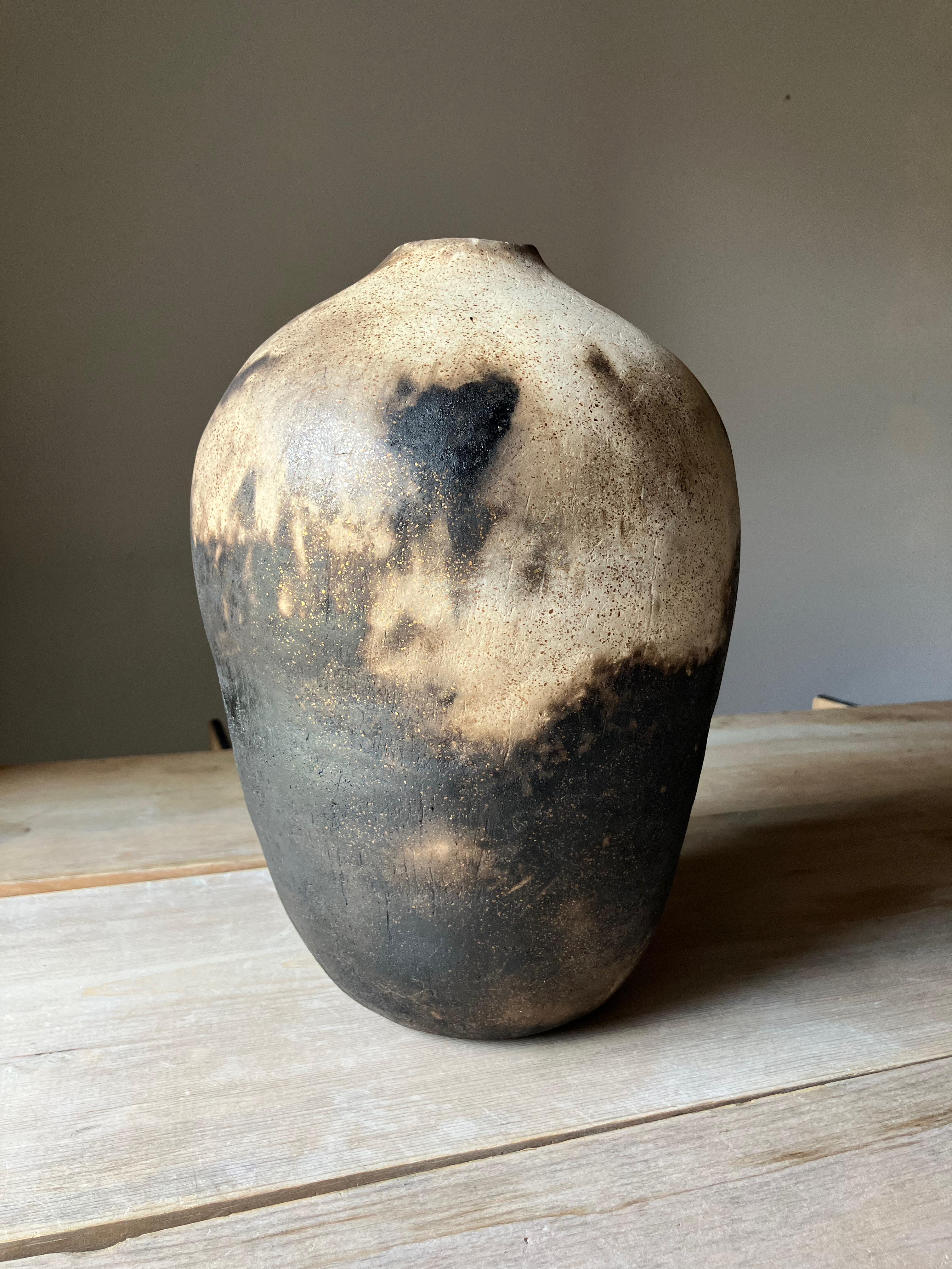 A ceramic bottle made by my hand, scraped and coiled into shape from micaceaous white earthenware clay and then burnished with leather and a water worn stone until it shines like silk. 

The work is fired multiple times, the final in a primitive