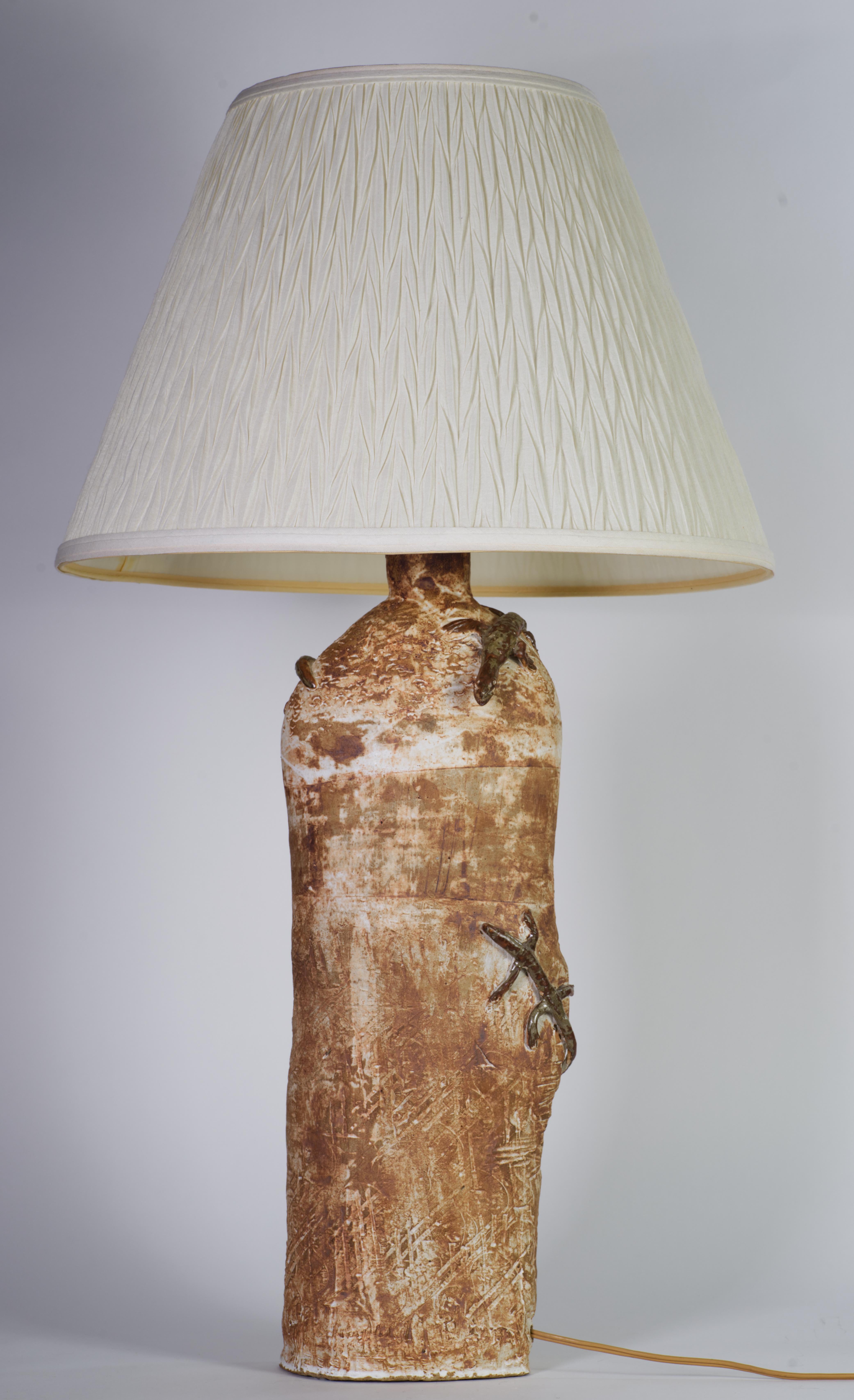  Cette lampe de table en poterie de studio, unique et sculpturale, est tournée à la main et décorée de figures de lézards abstraites et fantaisistes. Les lézards sont réalisés en relief et décorés d'une glaçure brillante brun chocolat et grise,