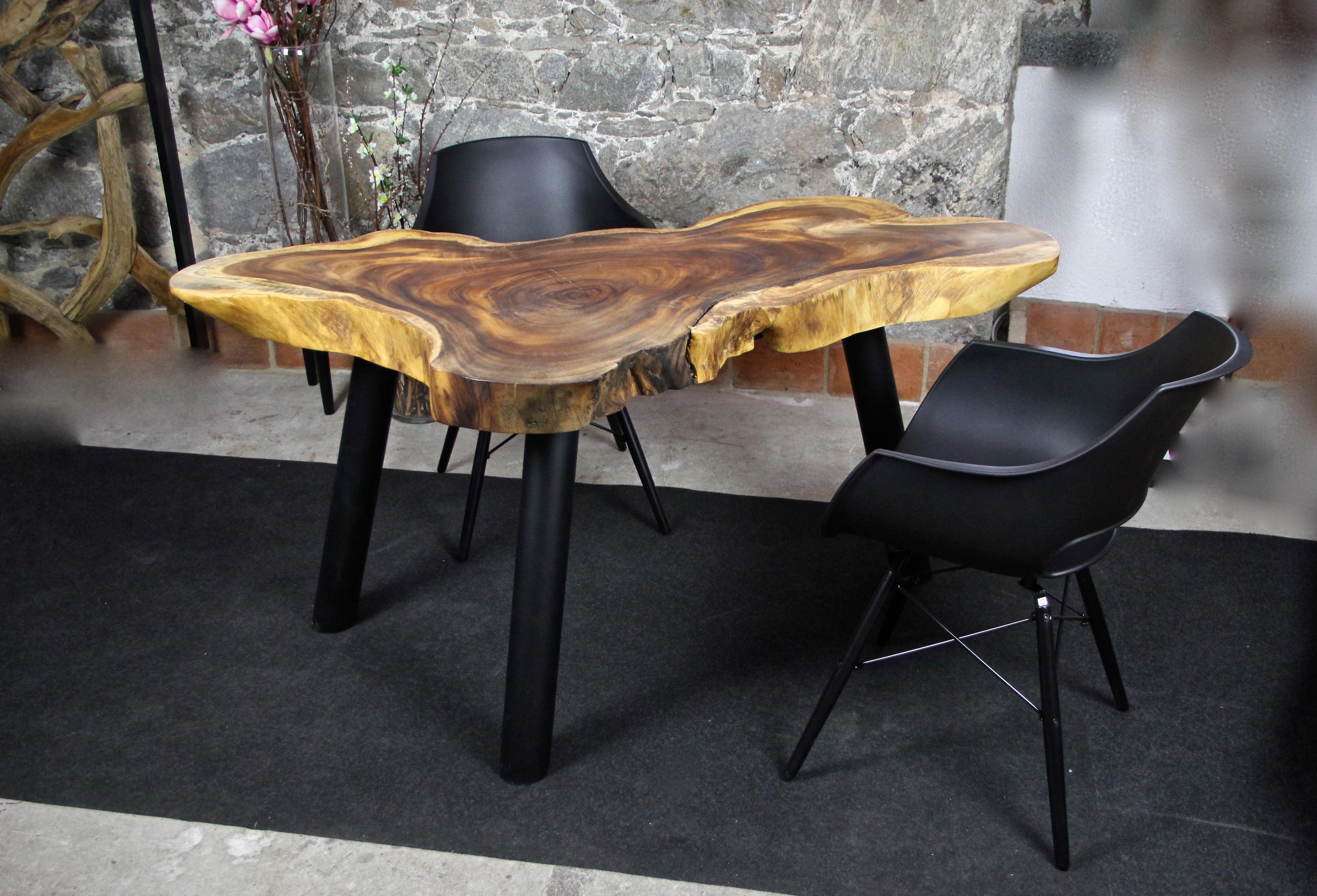 Unusual shaped organic modern Suar wood dining table. Standing on three massive round black metal feet, this extraordinary mid-sized dining table or coffee table (for four persons) stands out with its unique shape, grain and coloration. The