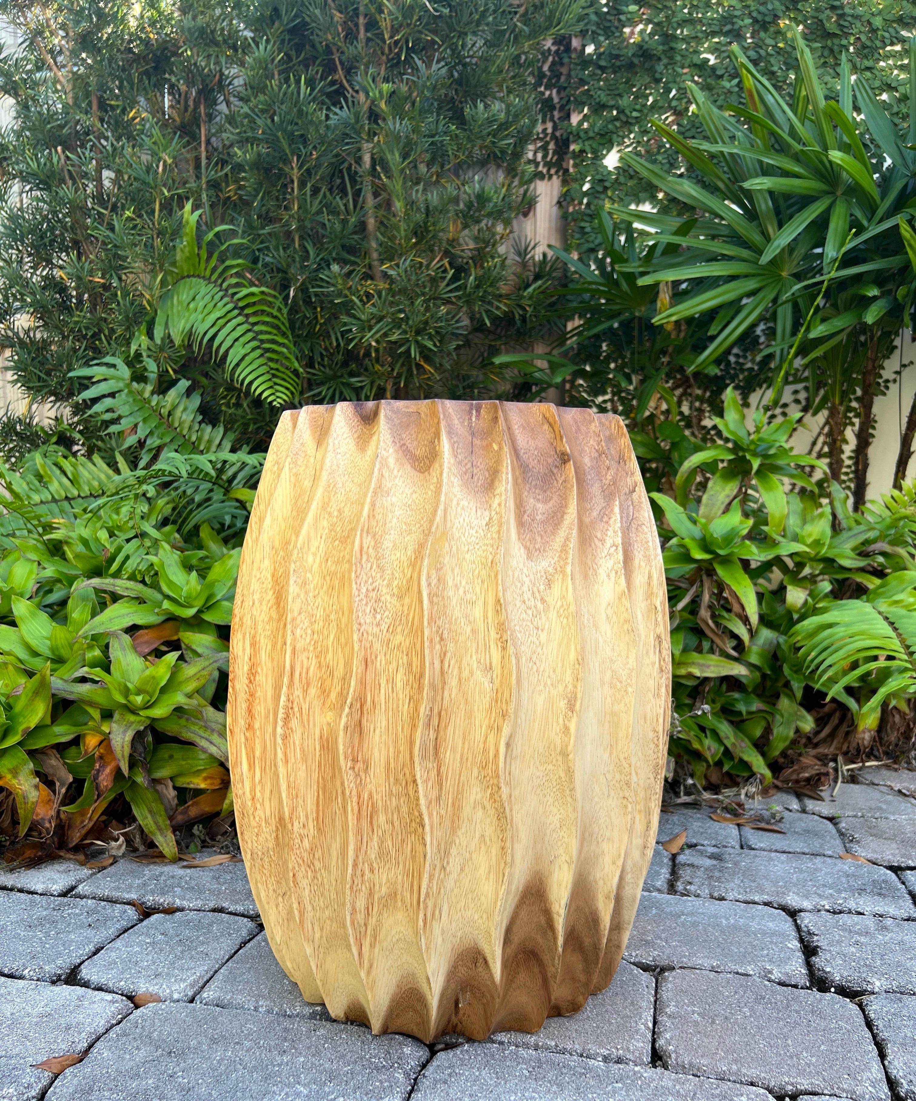 Organic modern sculptural side table with fluted design. This versatile piece can be used as a stool, a pedestal, or a drum table. Comprised of reclaimed suar wood, the drum table features hand carved fluted sides with wave formation. Each table is