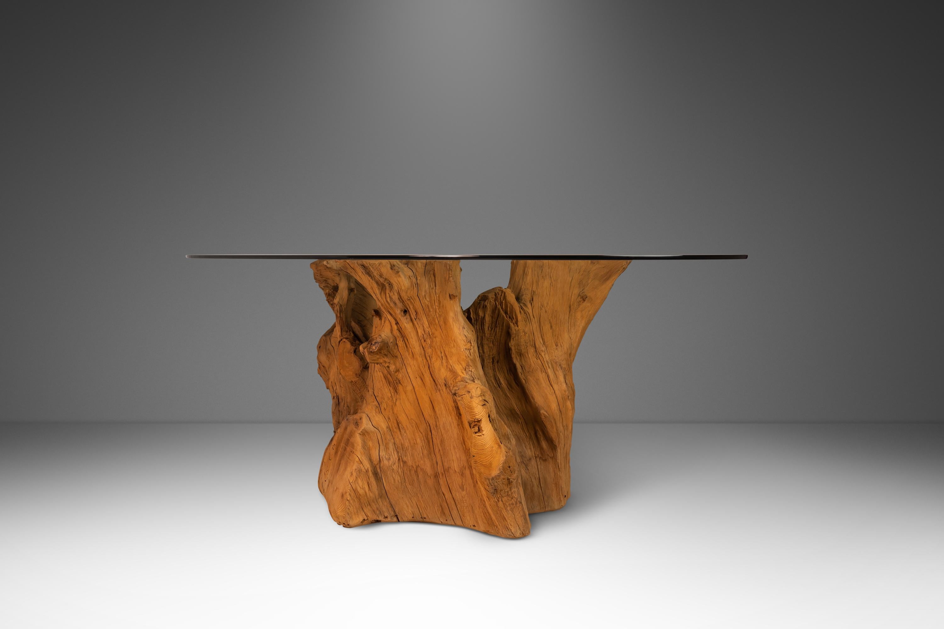 Introducing the ultimate in bohemian chic luxury: a one-of-a-kind cypress root dining table with an oval, beveled-edge glass top. This architectural masterpiece is handcrafted from a naturally fallen Florida Cypress tree, making it not only high end