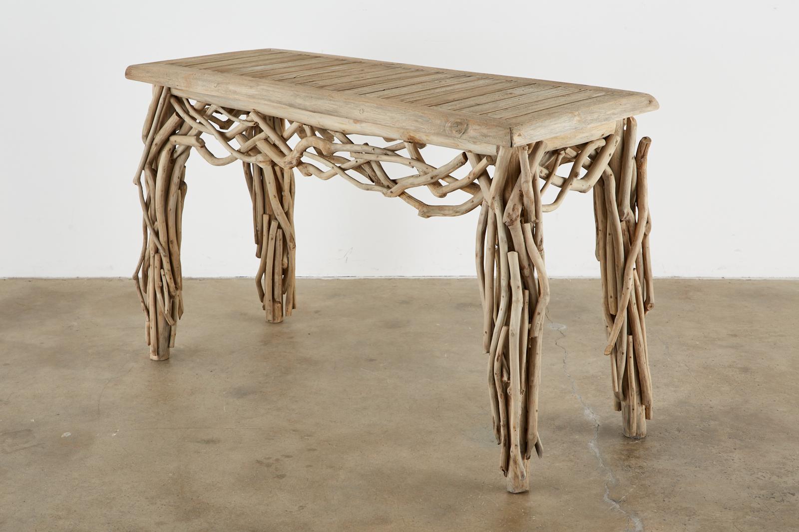 California coastal driftwood branch console table or sofa table made in the organic modern style. Constructed from a bleached teak wood frame with thick 2 inch planks and covered with beautifully weathered driftwood branches. Artison made with