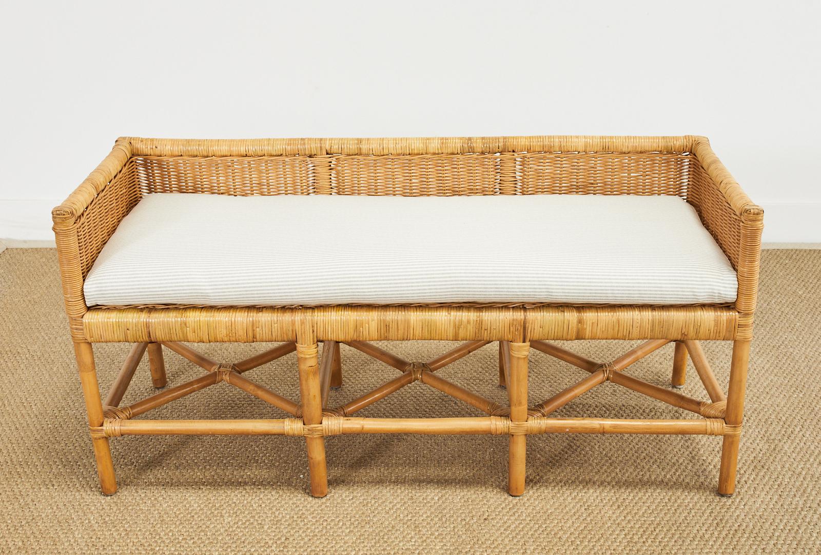 Charming rattan and wicker bench seat or settee made in the organic modern style by Tommy Hilfiger. The rectangular bench features a rattan frame with eight rattan pole legs. The rattan is covered with woven wicker and topped with a fitted seat