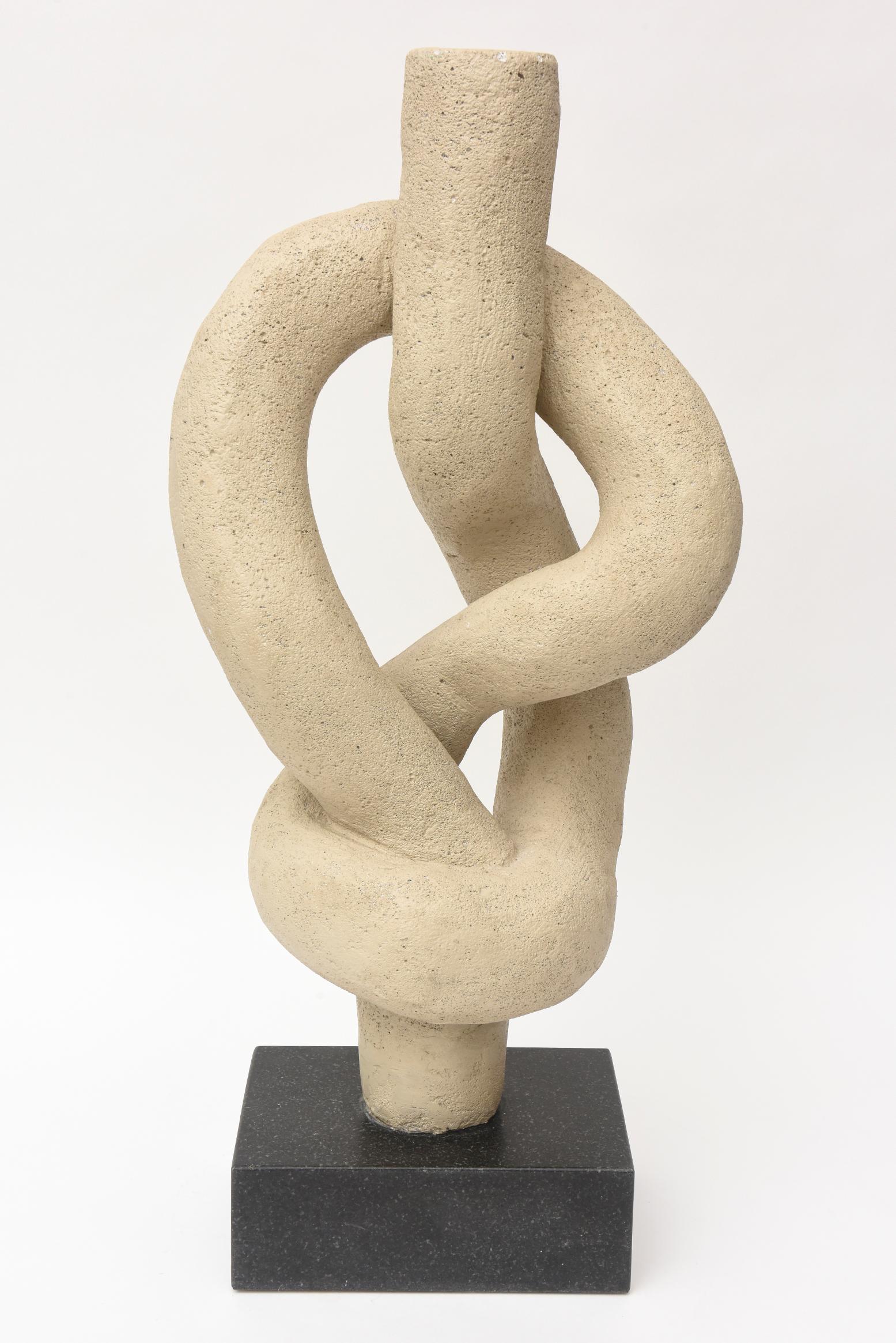 This substantial and tall organic modern sculpture is a mixed composition of cement, plaster and resin on a marble base. It is textural and has a pebbled finish of some sort. All is original. It's twisted and intertwined forms are like knotted