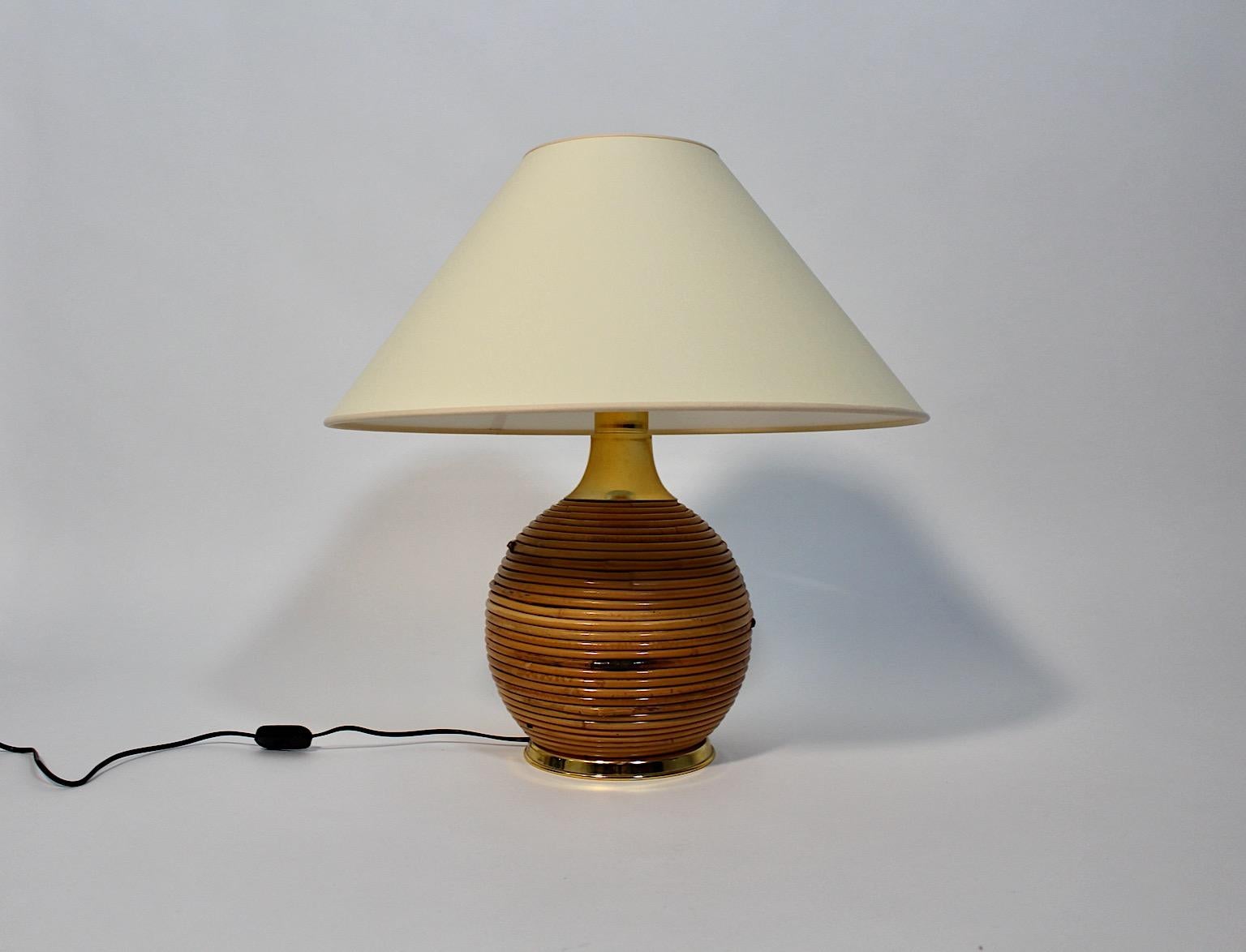 Lampada da tavolo vintage moderna e organica in rattan e metallo dorato degli anni '70 in Italia.
Una splendida lampada da tavolo con una base rotonda rivestita in rattan di colore marrone caldo e un paralume sostituito fatto a mano di colore
